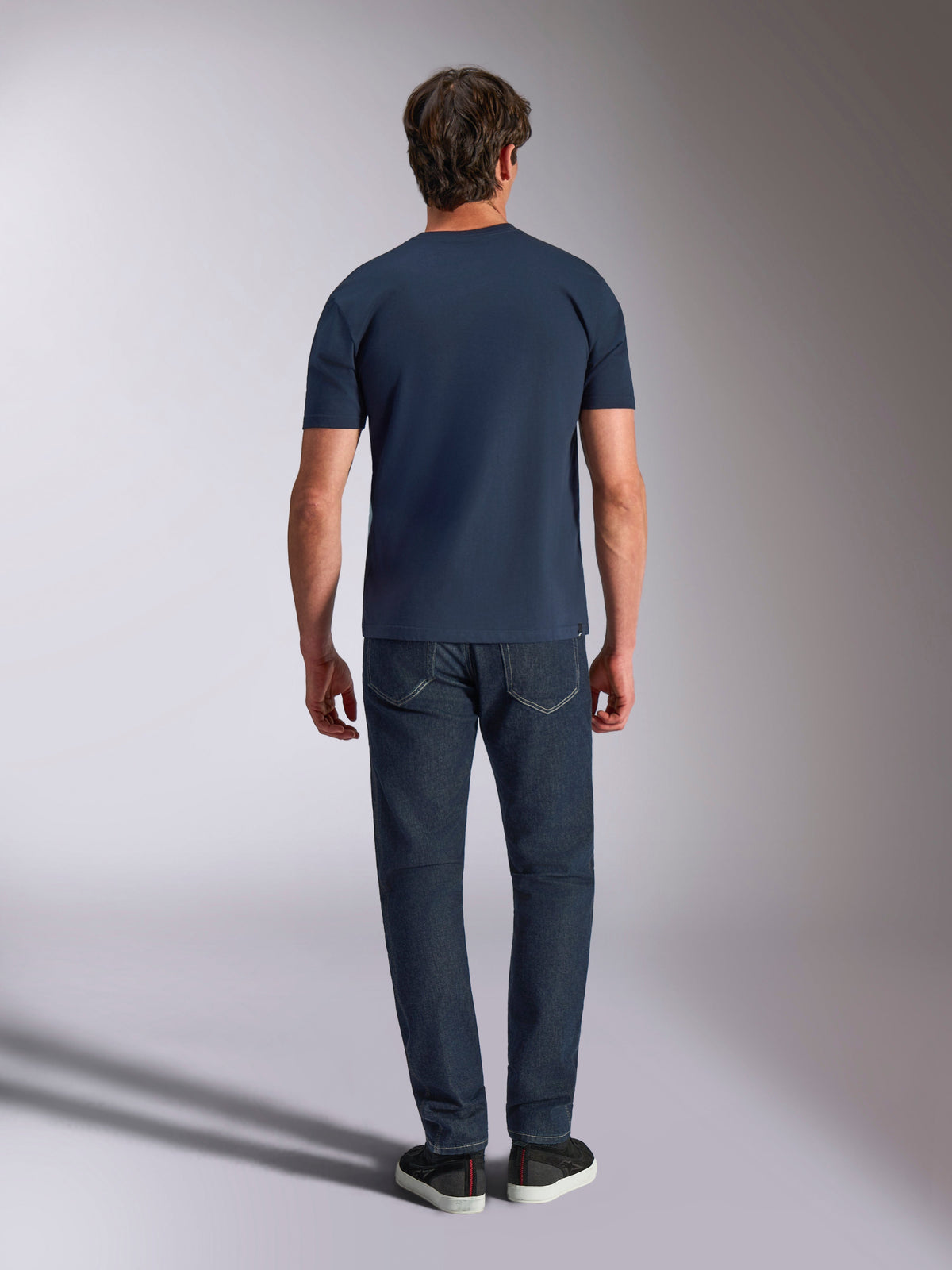 Alpinestars Ageless Shadow CSF Tee, Short Sleeve T-Shirt, Navy, back view of a model wearing the tee with dark jeans and black sneakers, casual motorsport streetwear.