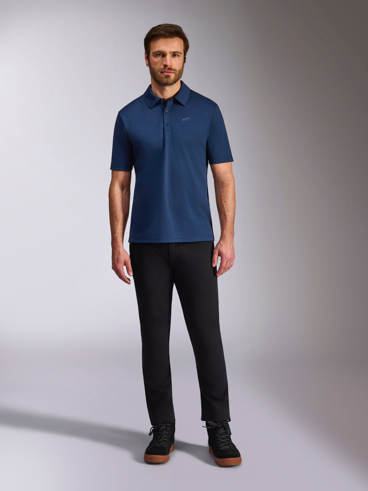 Alpinestars Impetus Sport Polo, Short Sleeve Polo Shirt, Navy Blue, small silver Astars logo on chest, three-button placket, worn by model with black pants and boots, casual motorsport-inspired sportswear