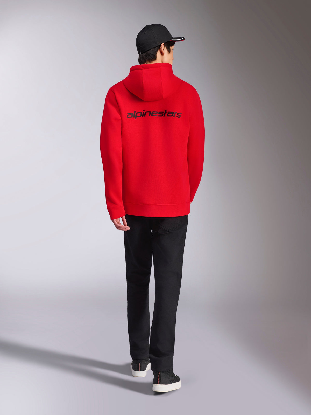 Alpinestars Transverse Hoodie, Red casual streetwear, back view featuring black Alpinestars wordmark logo, hooded fleece jacket, styled with black cap and black trousers