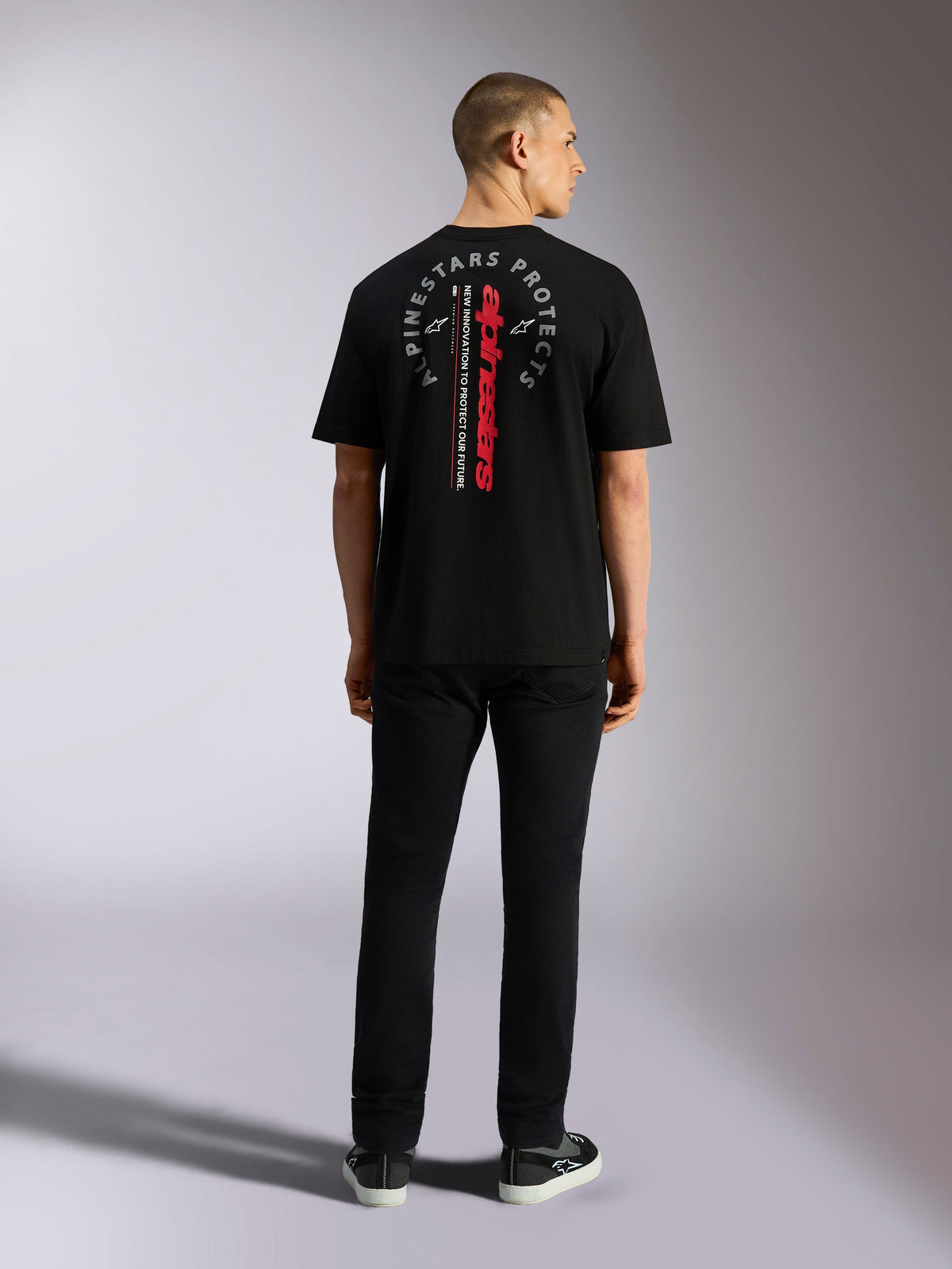 Alpinestars Overhang Oversized CSF Tee, Short Sleeve T-Shirt, Black, featuring vertical red Alpinestars wordmark and grey circular graphic on the back, worn by model from behind, casual motorsport streetwear