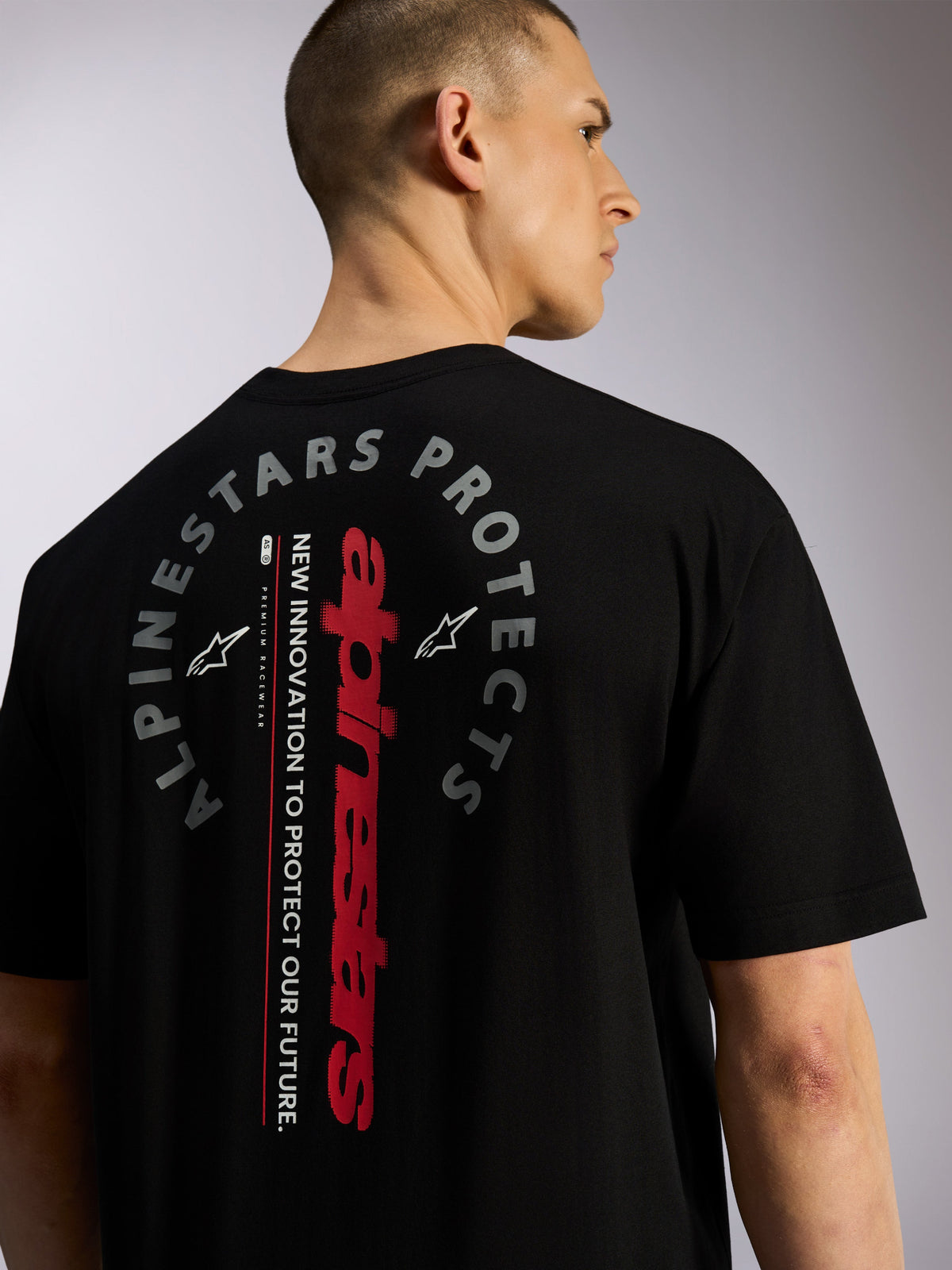 Alpinestars Overhang Oversized CSF Tee, Short Sleeve T-Shirt, Black, back view featuring vertical red Alpinestars wordmark and circular "Alpinestars Protects" graphic, casual motorsport-inspired streetwear