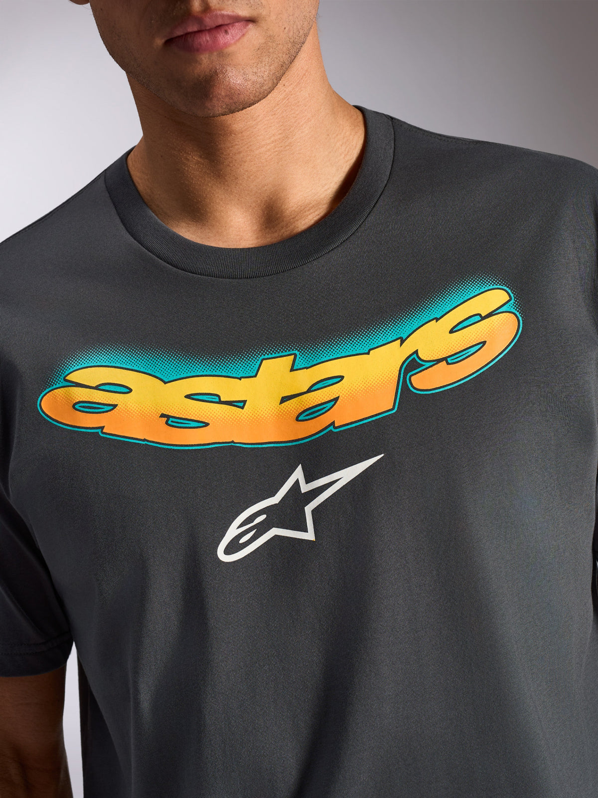 Alpinestars Ellipsoid CSF Tee, Short Sleeve T-Shirt, Charcoal Gray, curved 'astars' wordmark with yellow and orange gradient and teal dot pattern, white Alpinestars star logo, casual motorsport-inspired apparel