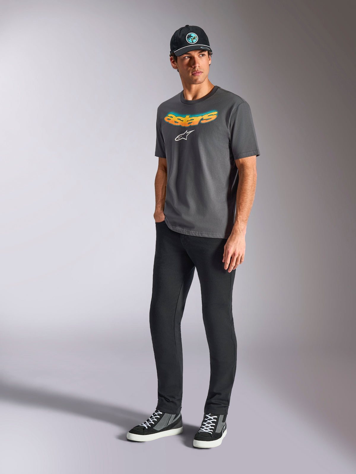 Alpinestars Ellipsoid CSF Tee, Short Sleeve T-Shirt, Charcoal Gray, featuring curved astars wordmark with color gradient and white logo, worn by model with black pants and cap, casual motorsport streetwear