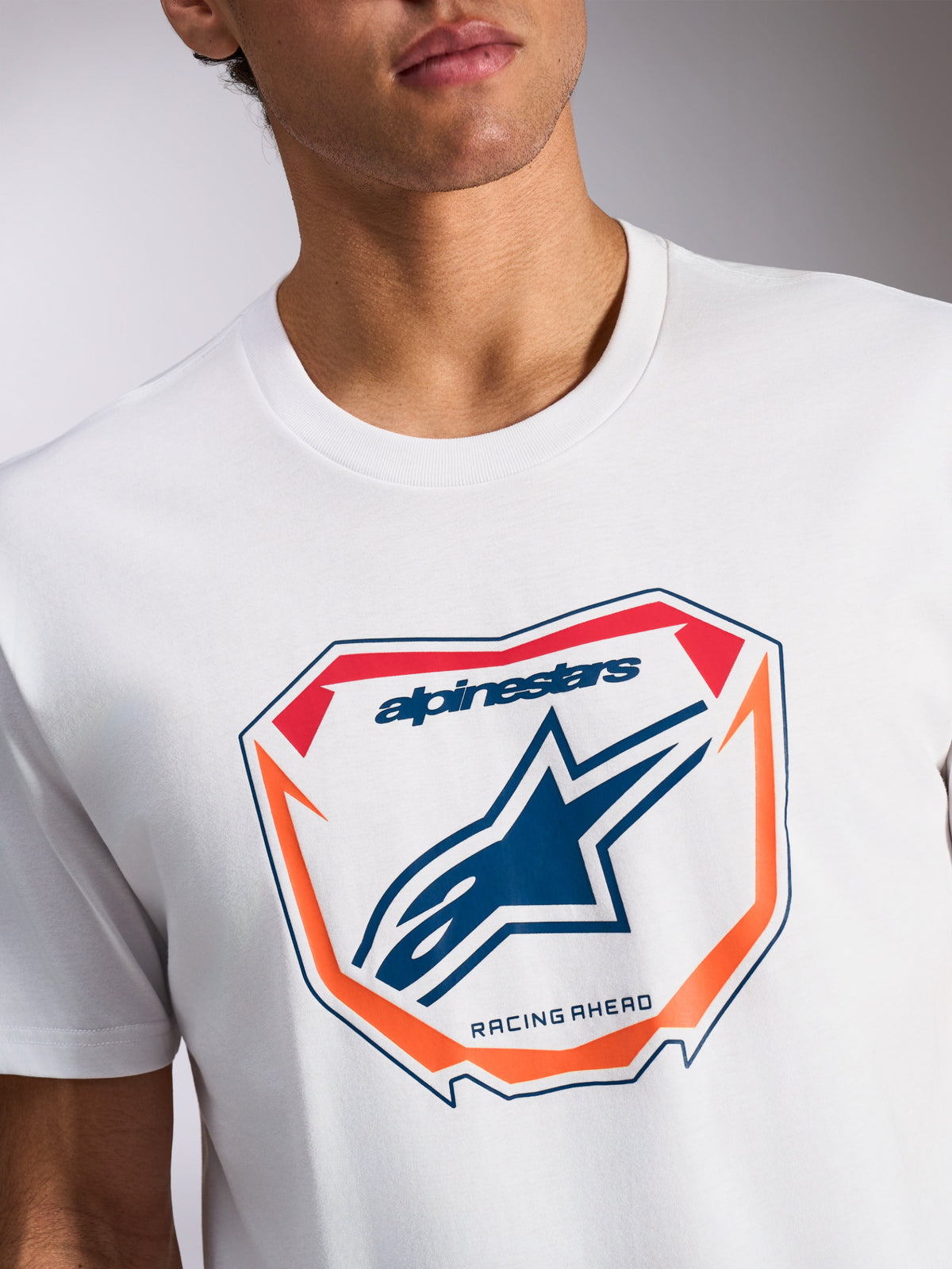 Alpinestars Plate CSF Tee, Short Sleeve T-Shirt, White, Front MX Plate Graphic with Blue Astars Logo and 'Racing Ahead' text, Orange and Red accents, Casual Motorsport Sportswear