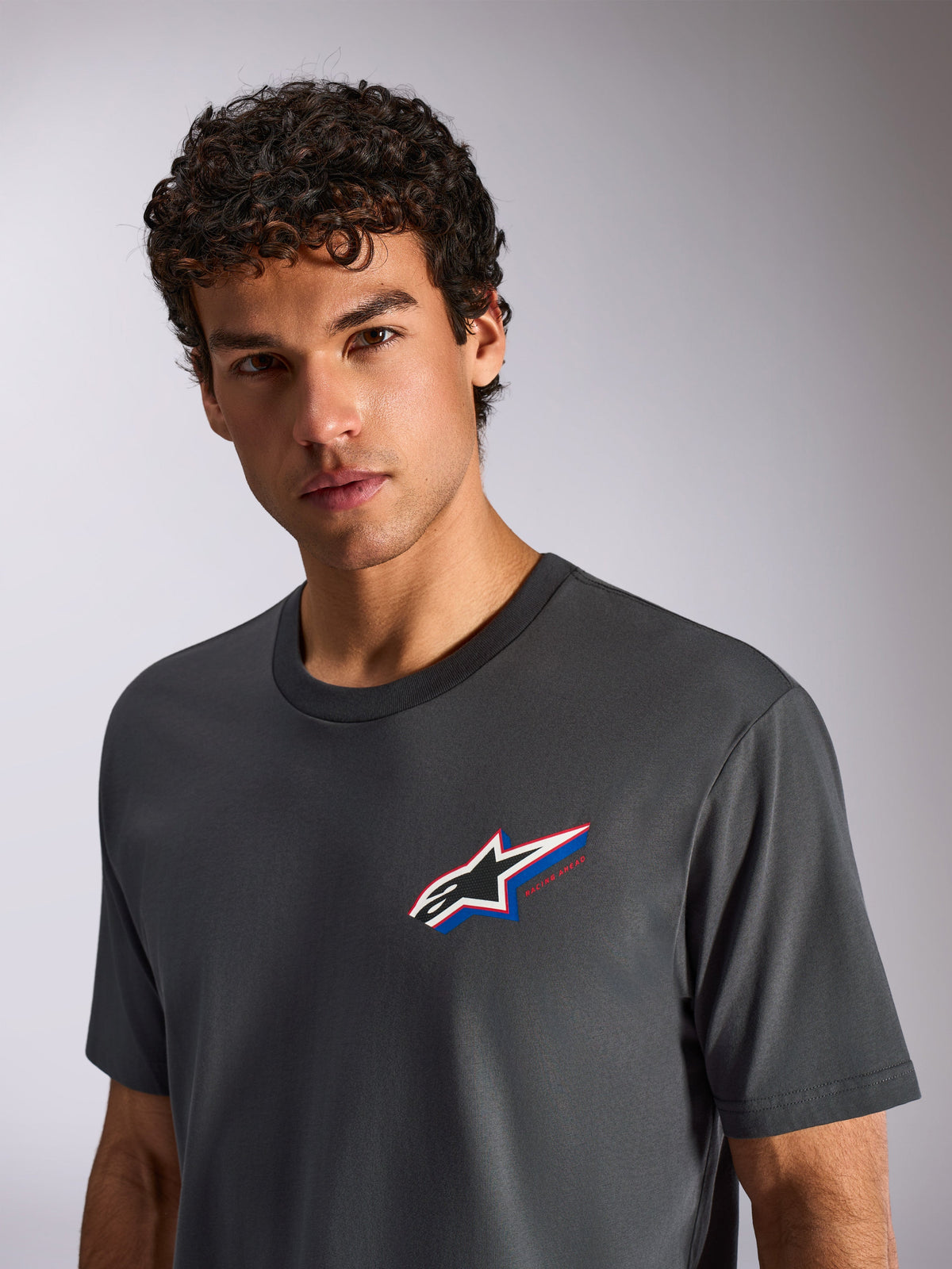 Alpinestars Angler CSF Tee, Short Sleeve T-Shirt, Charcoal Gray, worn by a male model, featuring a multi-color Astars logo on the chest, casual motorsport streetwear