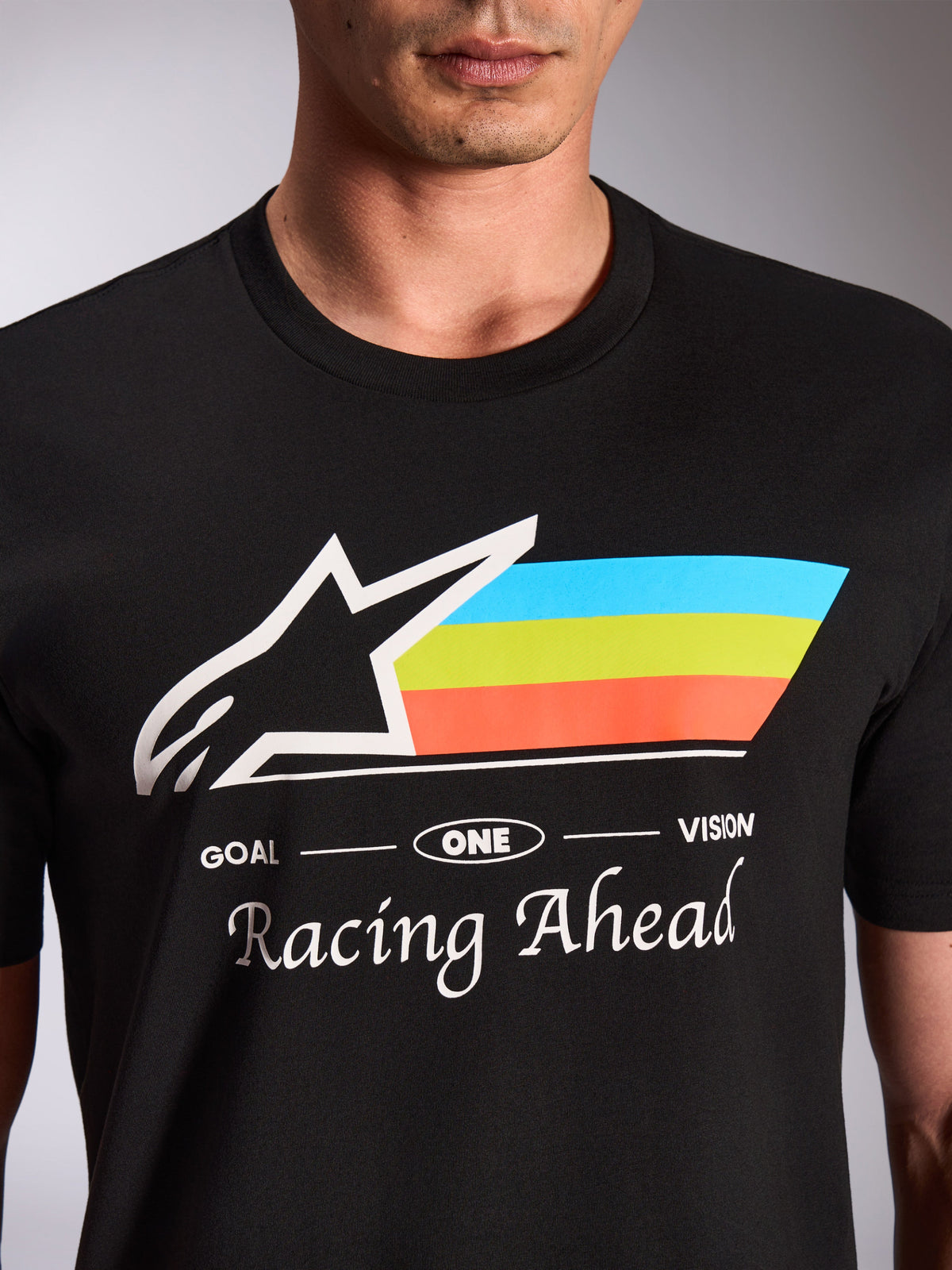Alpinestars Trifecta CSF Tee, Short Sleeve T-Shirt, Black, close-up of front graphic with white Astars logo and tri-color blue green and orange stripes, 'Racing Ahead' text, casual motorsport streetwear
