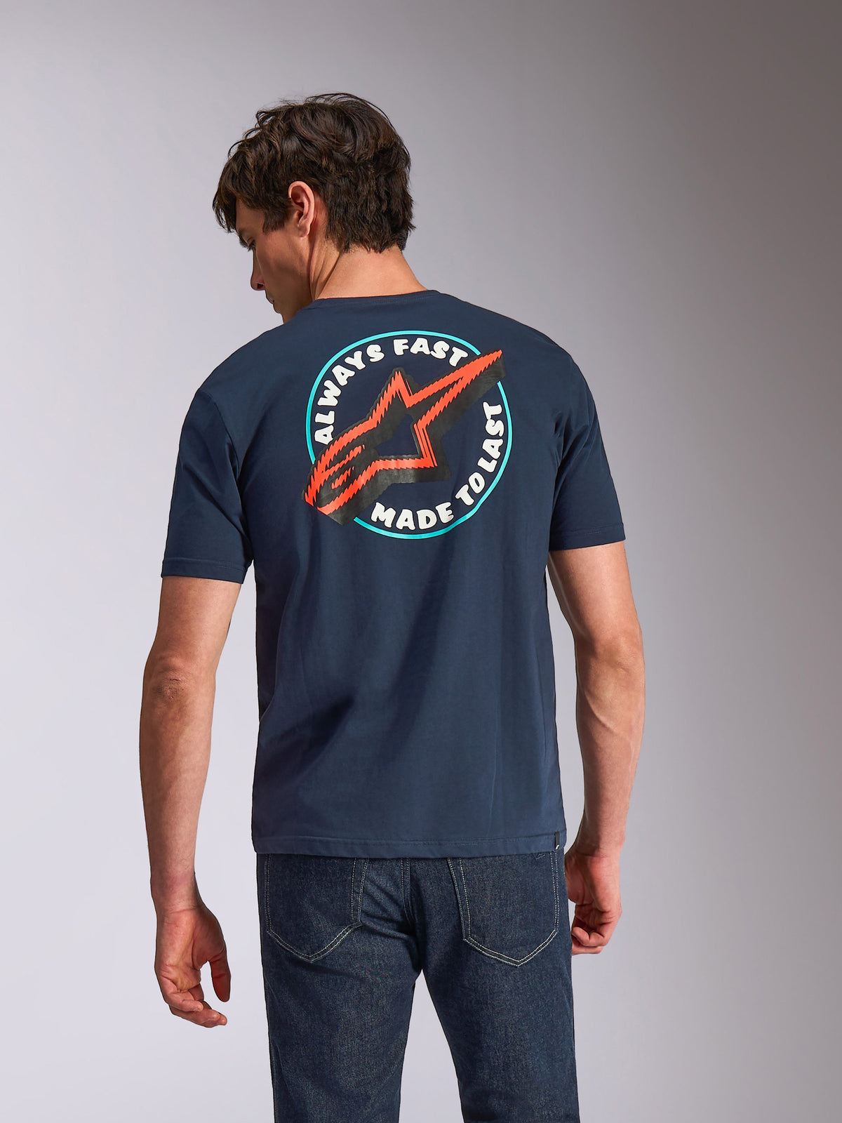 Alpinestars Aorbit CSF Tee, Short Sleeve T-Shirt, Navy Blue, back view on model featuring circular 'Always Fast Made to Last' graphic with red Astars logo, casual motorsport-inspired streetwear