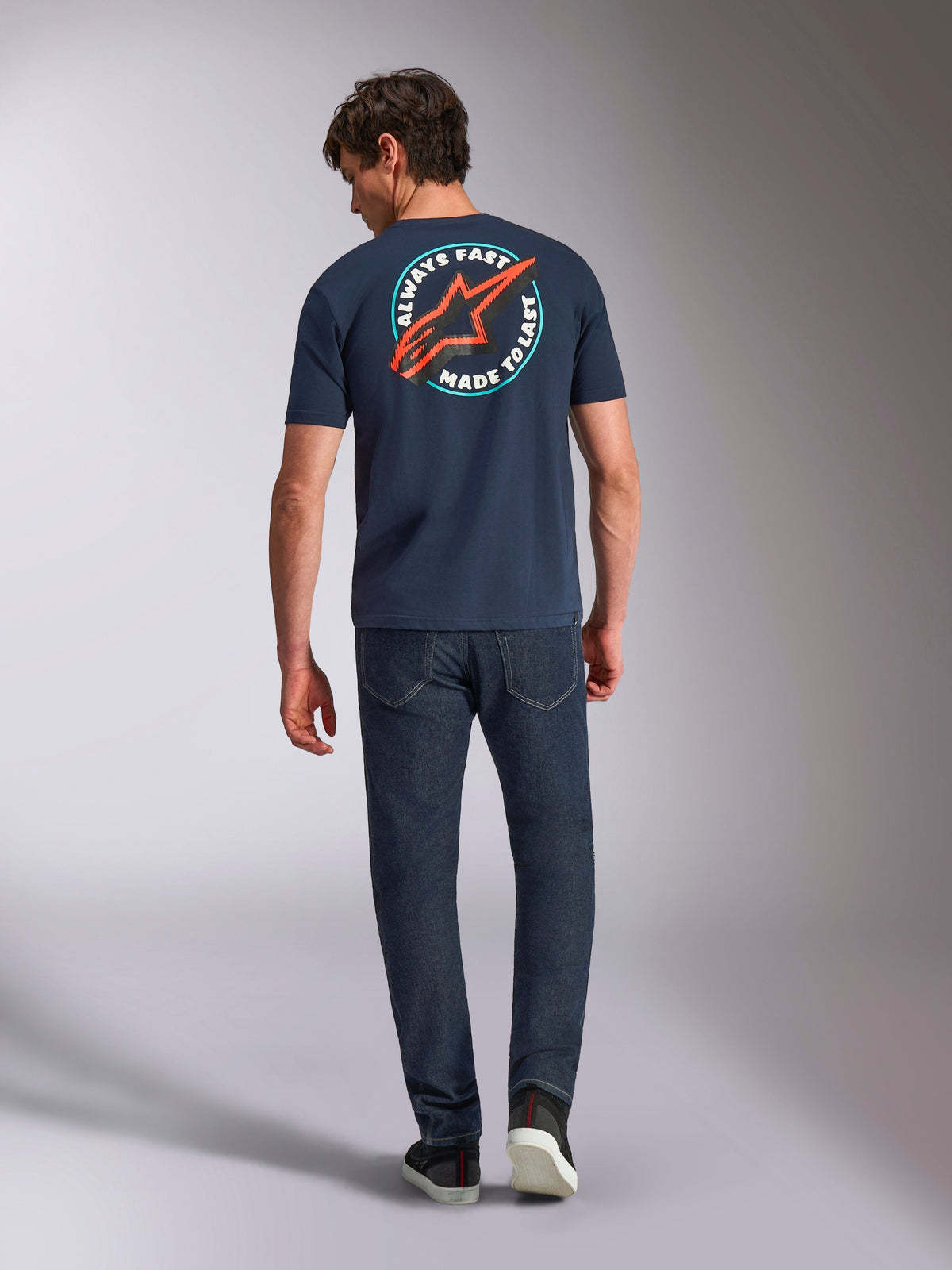 Alpinestars Aorbit CSF Tee, Short Sleeve T-Shirt, Navy, back view on model featuring large circular graphic with red Astars logo and 'Always Fast Made to Last' text, casual motorsport streetwear