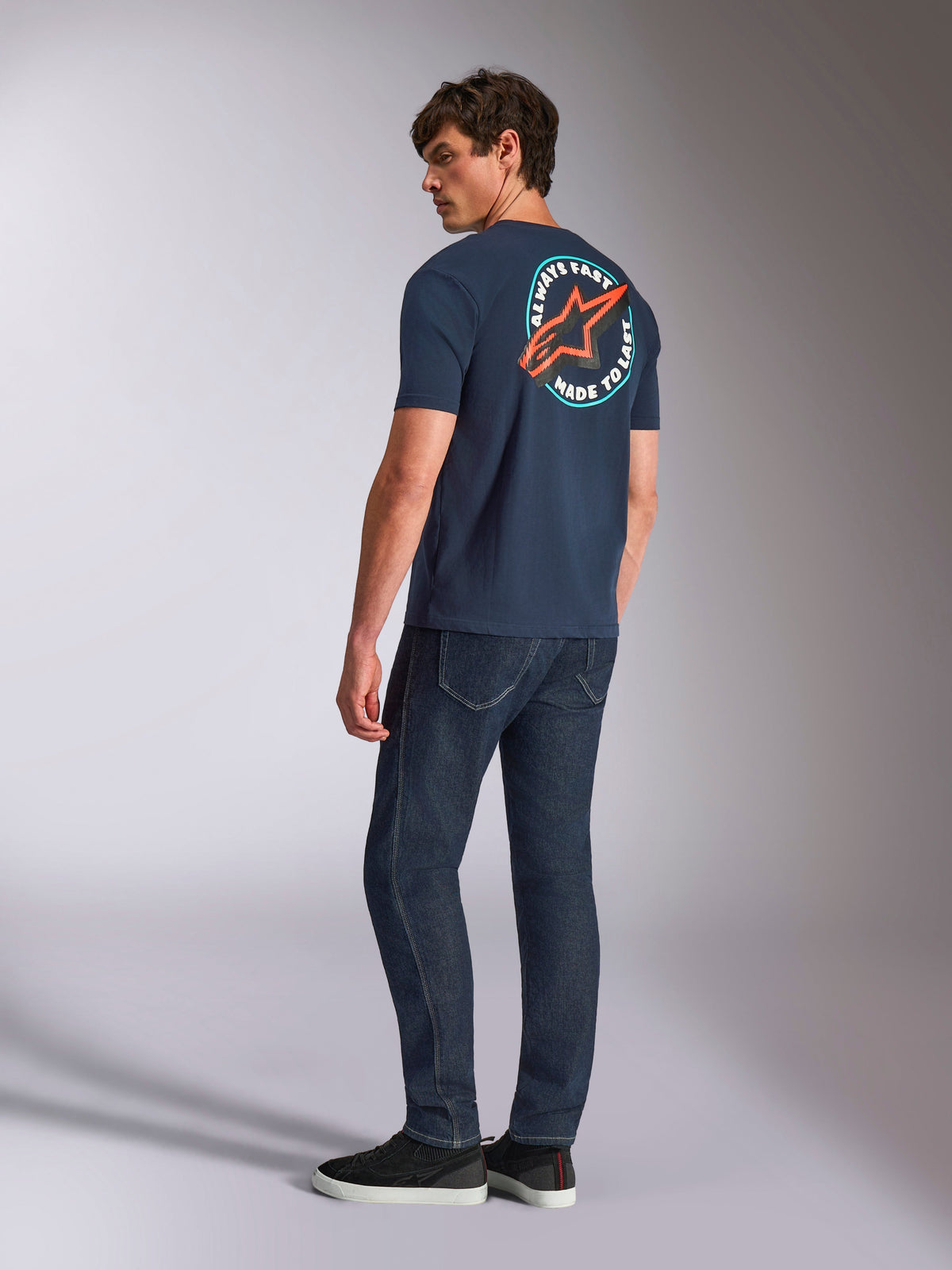 Alpinestars Aorbit CSF Tee, Short Sleeve T-Shirt, Navy Blue, back view on model featuring a large circular Astars logo with 'Always Fast Made to Last' graphic, casual motorsport-inspired streetwear