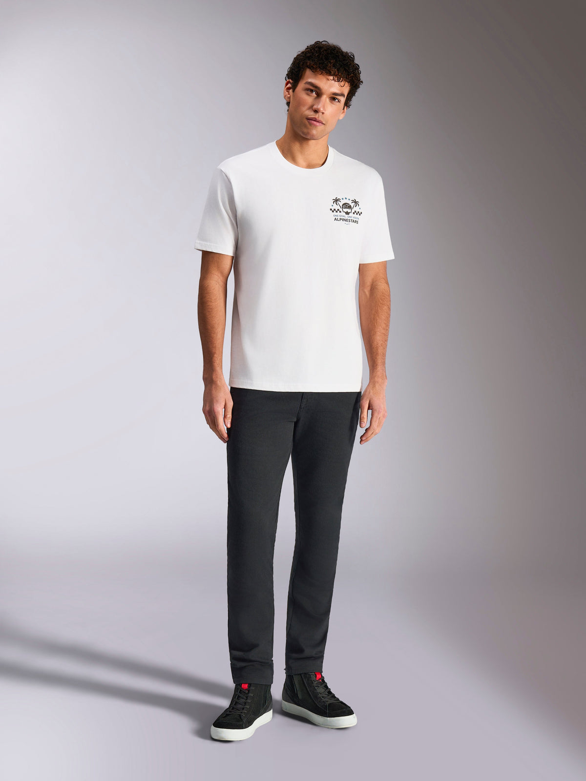 Alpinestars Order CSF Tee, Short Sleeve T-Shirt, White, Small black chest graphic with helmet and palm trees, casual motorsport streetwear, worn by model with black pants and sneakers