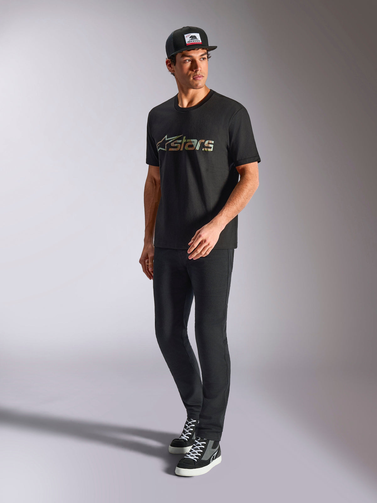 Alpinestars Verdure Camo CSF Tee, Short Sleeve T-Shirt, Black, featuring a Camo Fill Astars Logo on the chest, worn by a model with a black cap and pants, casual motorsport streetwear