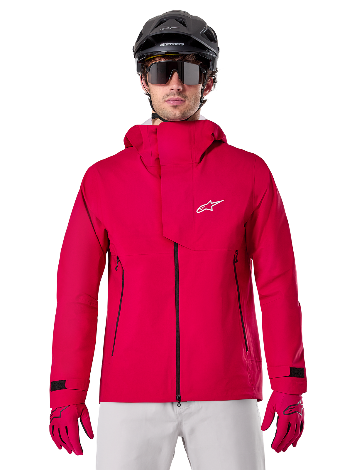 Alpinestars A-Dura Elite Waterproof Jacket, Mountain Bike Rain Jacket, Red Fluo, high collar with white Alpinestars logo, black zipper details, worn with matching gloves and black cycling helmet, technical waterproof cycling gear