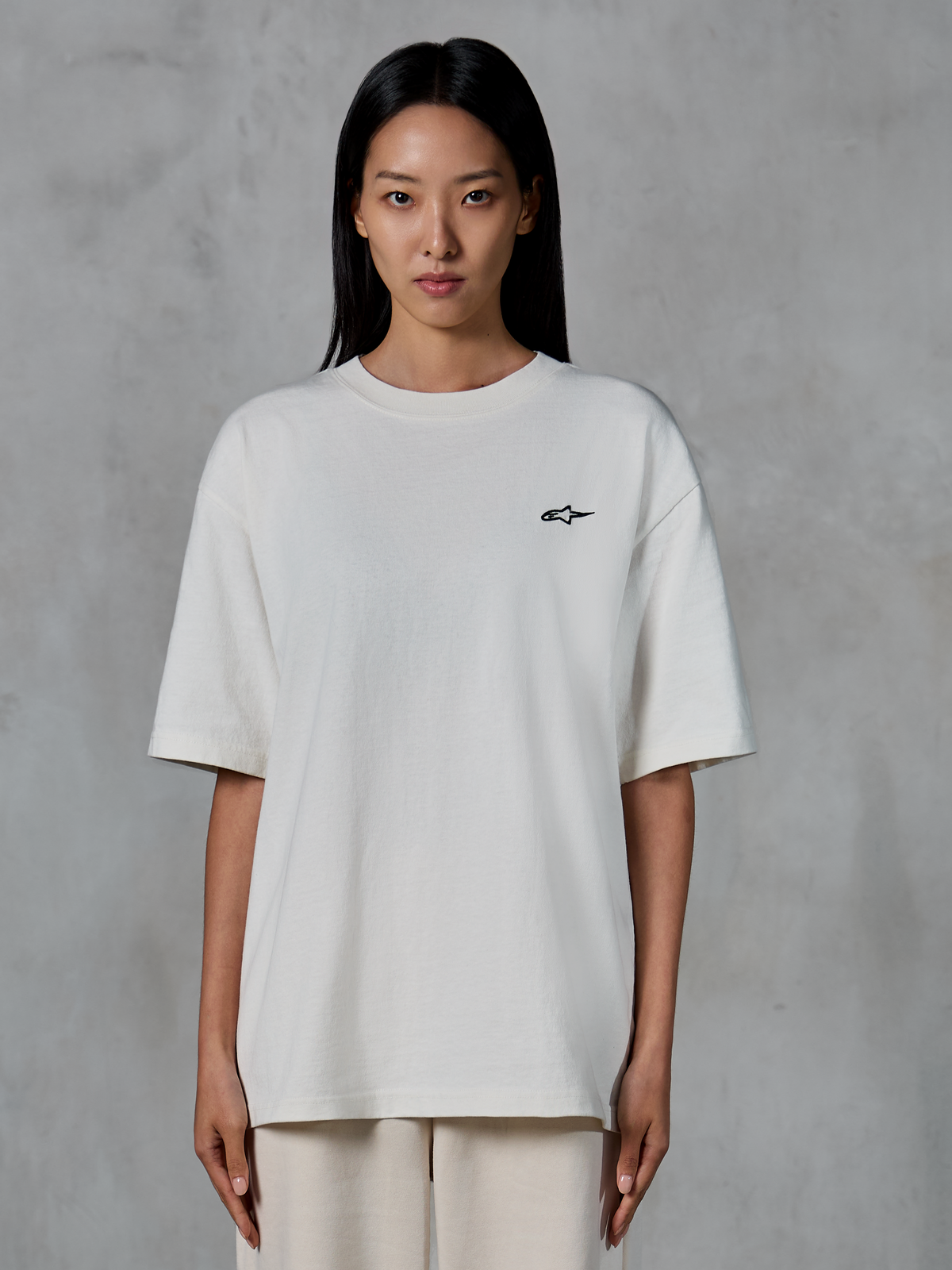 Alpinestars Essentials Ageless SS Tee, Short Sleeve T-Shirt, Off White, worn by female model, featuring a small black Alpinestars logo on the chest, relaxed fit, casual lifestyle streetwear