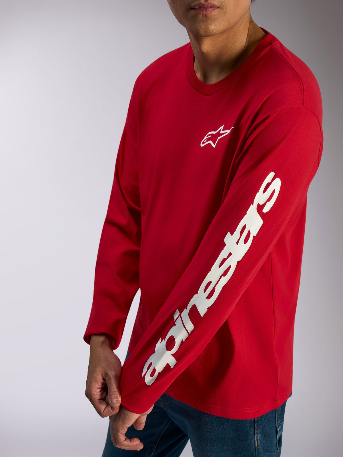 Alpinestars Trackside CSF Tee, Long Sleeve T-Shirt, Red, white Alpinestars logo on chest and bold wordmark on sleeve, casual motorsport streetwear worn with blue jeans
