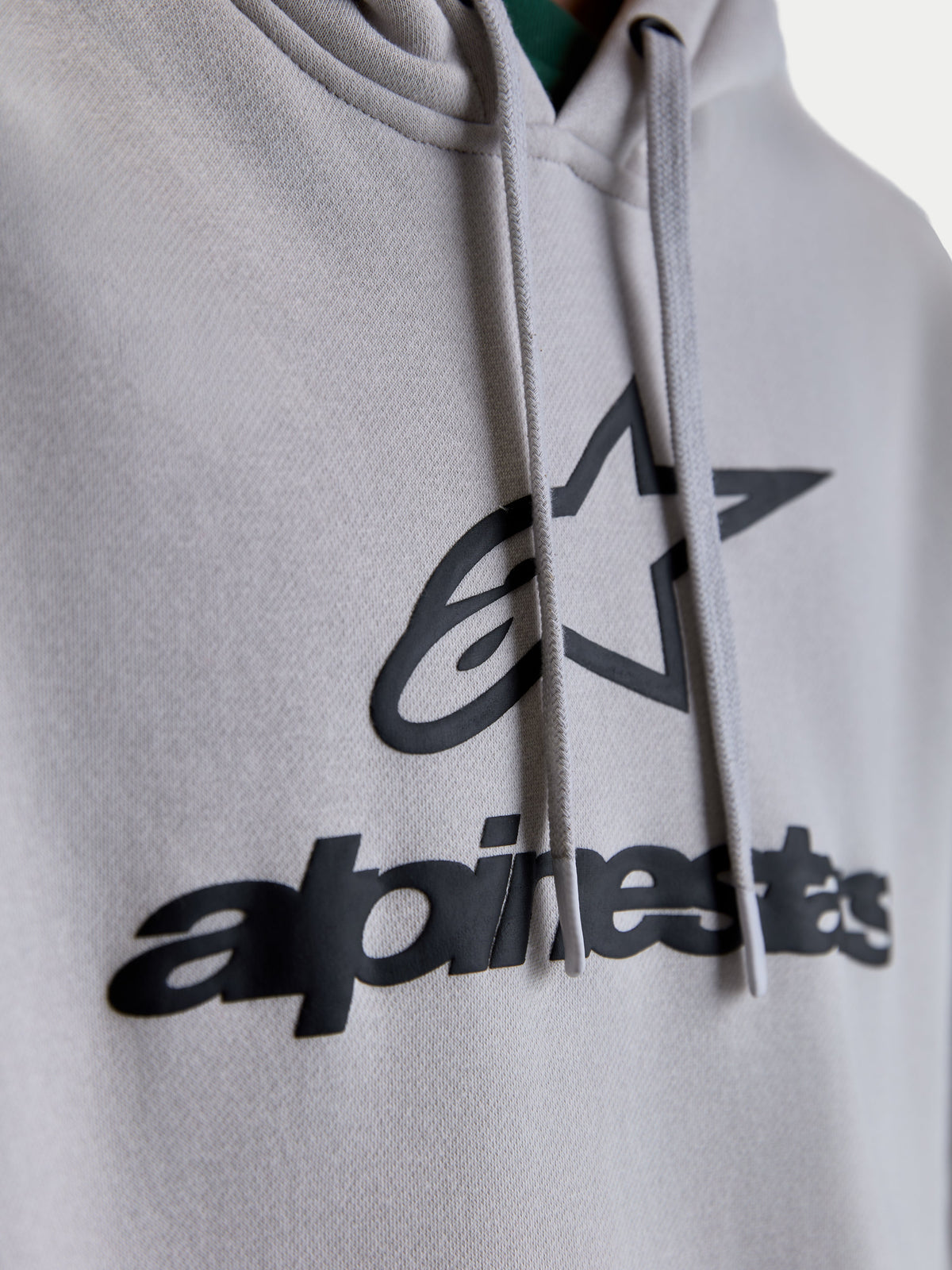 Alpinestars Prelude Oversized Hoodie, Sportswear Fleece Pullover, Unisex, Cement Gray and Black, Close-up of puff-print Alpinestars chest logo and flat hood drawcords.