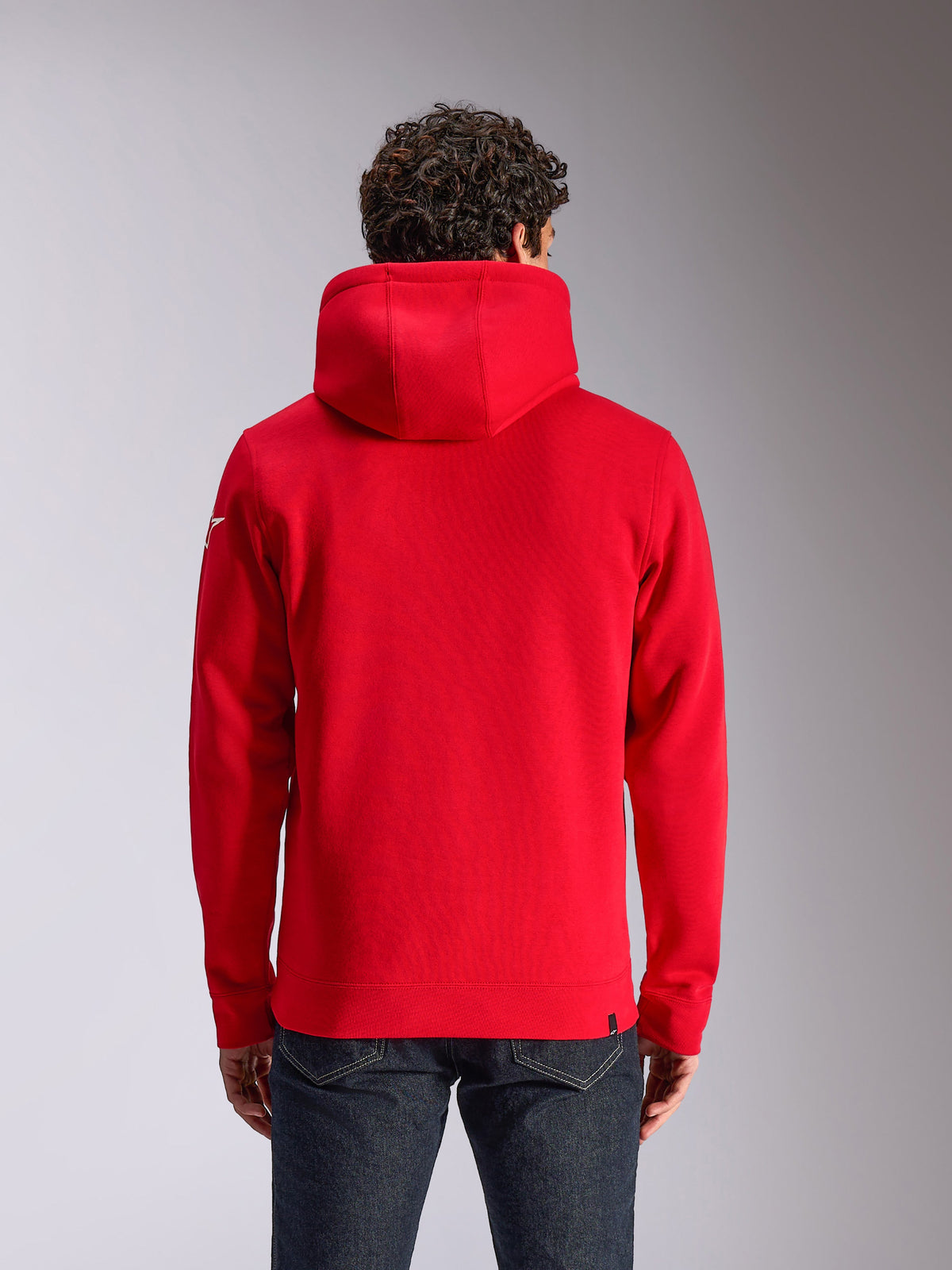 Alpinestars Linear Wordmark V3 Hoodie, rear view of a red hooded pullover fleece, featuring a white Ageless logo on the sleeve, ribbed cuffs and hem, casual motorsport-inspired streetwear