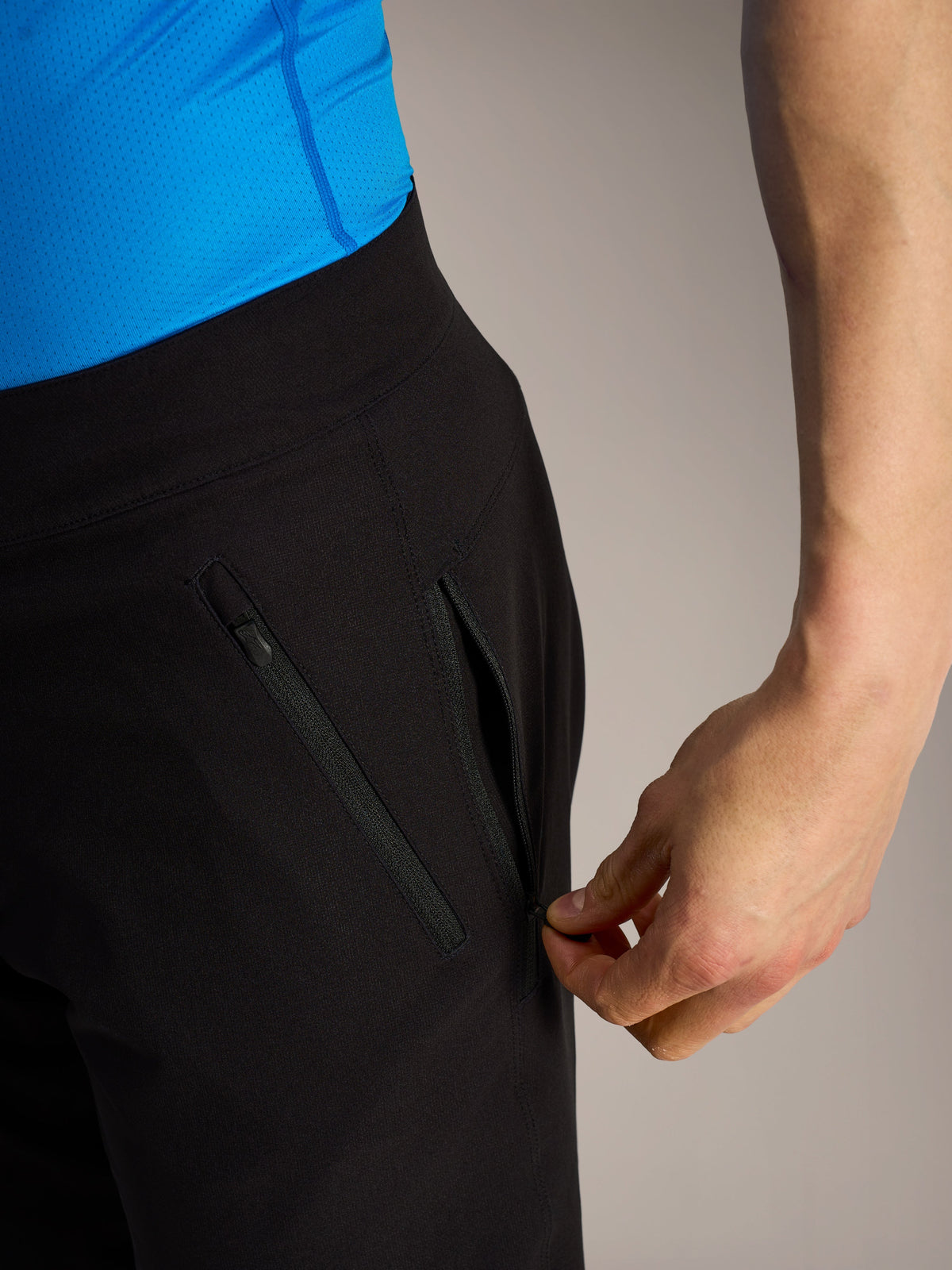 Black Alpinestars A-Dura Ride MTB shorts, close-up of a hand opening one of the three secure zippered side pockets.