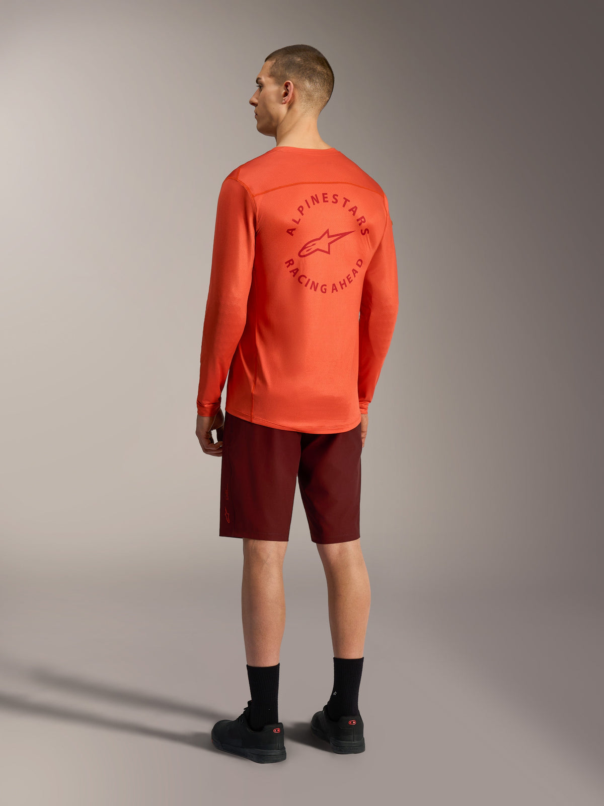 Orange A-Dura Air long-sleeve jersey with back graphic and bordeaux A-Dura Ride Shorts, performance MTB gear.