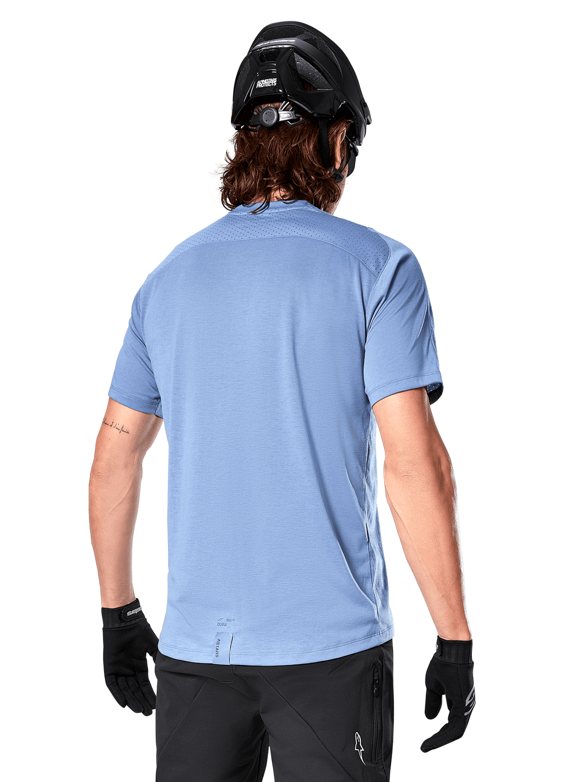 Alpinestars A-Dura Dri Astar Short Sleeve Jersey, MTB Jersey, Infinity Blue, back view showing mesh ventilation panels on shoulders and a longer drop tail, worn with a black MTB helmet and gloves, performance cycling gear