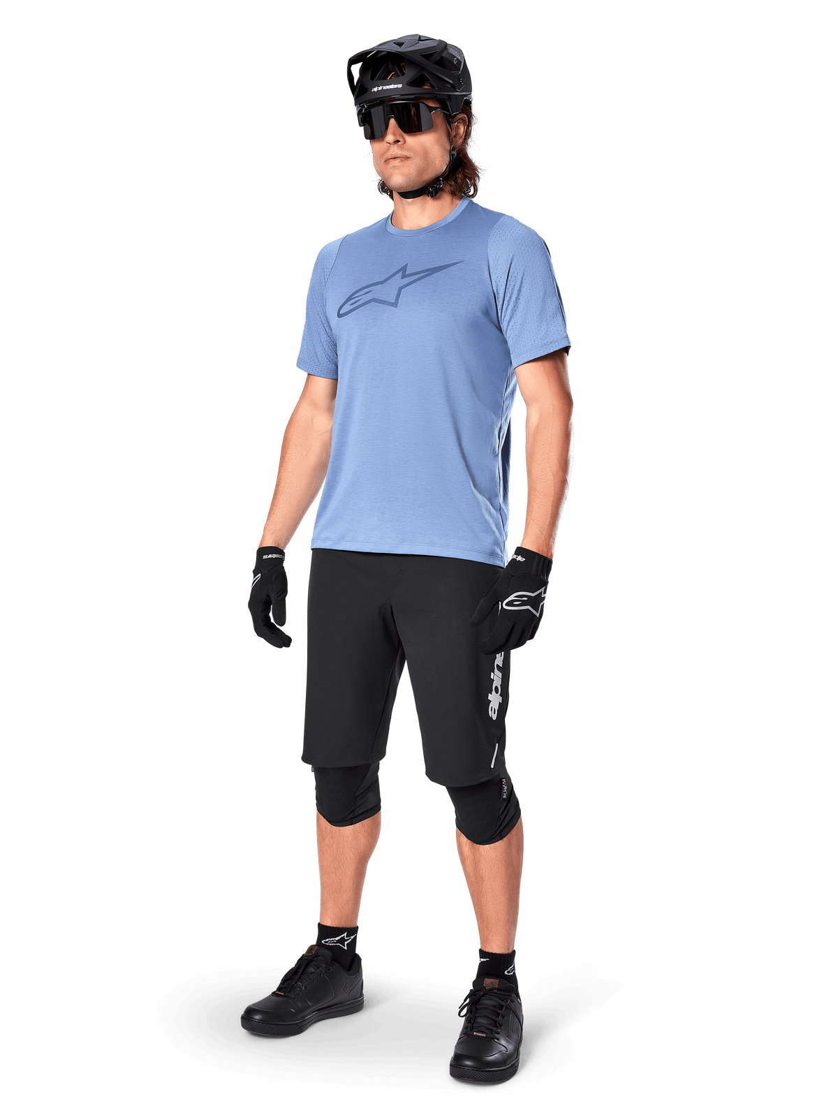 Male rider wearing the Alpinestars A-Dura Dri Astar Short Sleeve Jersey in Infinity Blue, paired with black MTB shorts, black helmet, sunglasses, knee pads, and gloves, complete mountain biking outfit