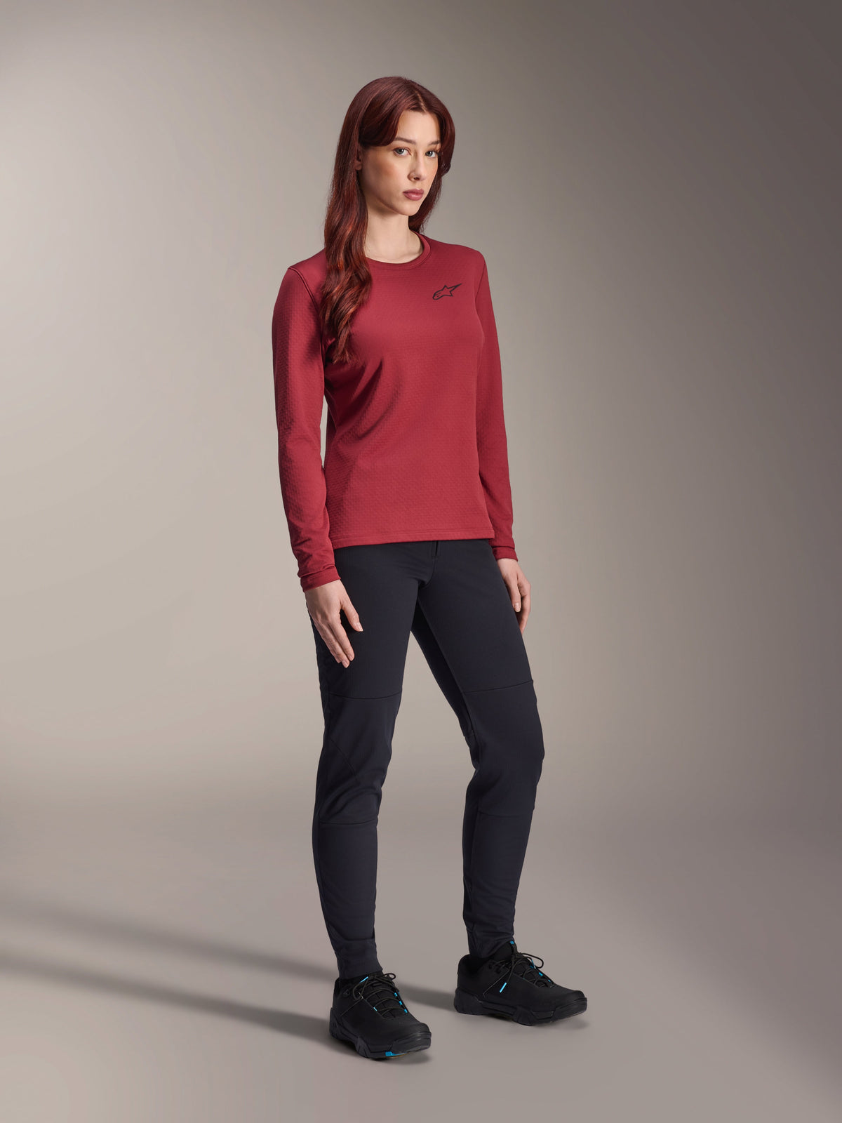 Alpinestars Stella A-Dura Thermal Jersey, Women's Long-Sleeve Mountain Bike Jersey, Burgundy, worn with black athletic pants and black shoes, crew neck with small black chest logo, functional and regular fit design for off-road cycling