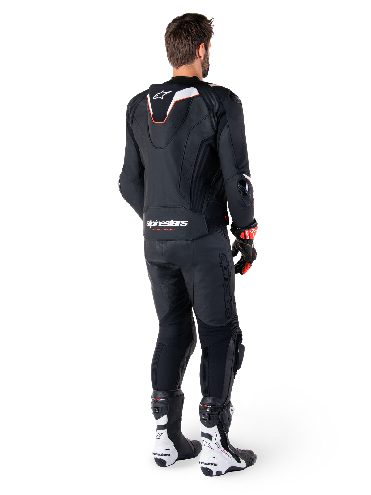 Rear view of a rider wearing the Alpinestars Missile V3 Ignition Leather Jacket in Black, featuring a slim sport Aero-hump with white and red accents, Alpinestars branding on the lower back, paired with matching black leather pants and black and white racing boots, professional sport riding outfit