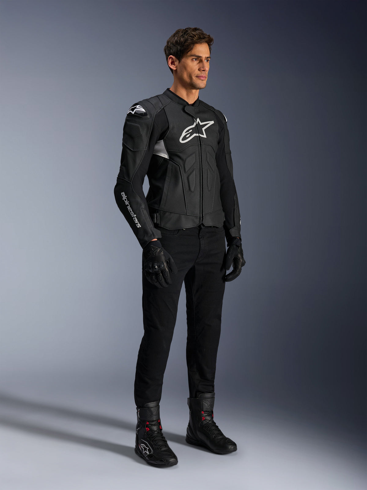 Alpinestars Dusk Airflow Leather Jacket, Black and White, modeled with black motorcycle pants, gloves, and boots, featuring perforated leather panels and white logo branding, sport road racing style.