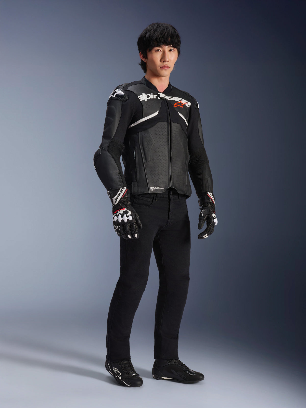 Alpinestars Atem V5 Leather Jacket, Motorcycle Racing Jacket, Black and White, worn with black pants and matching gloves, featuring white Alpinestars branding across the chest and protective shoulder armor.