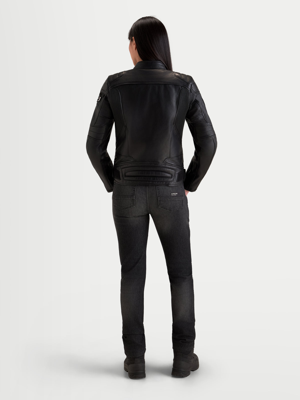 Alpinestars Revea Women Leather Jacket, women's urban motorcycle leather jacket in black, rear view on a model wearing dark jeans and riding boots, full-grain bovine leather construction