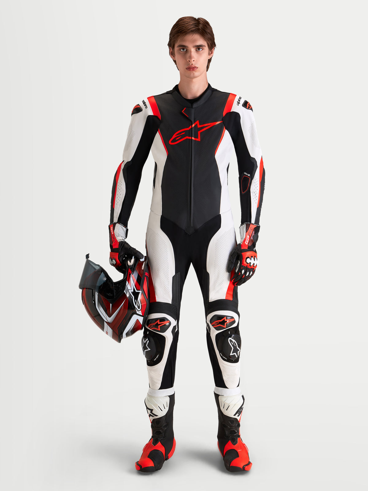 Alpinestars Missile V3 Leather Suit - 1 Piece, men's race-grade motorcycle leather suit in Black, White, and Red Fluo, featuring integrated protection and holding a racing helmet
