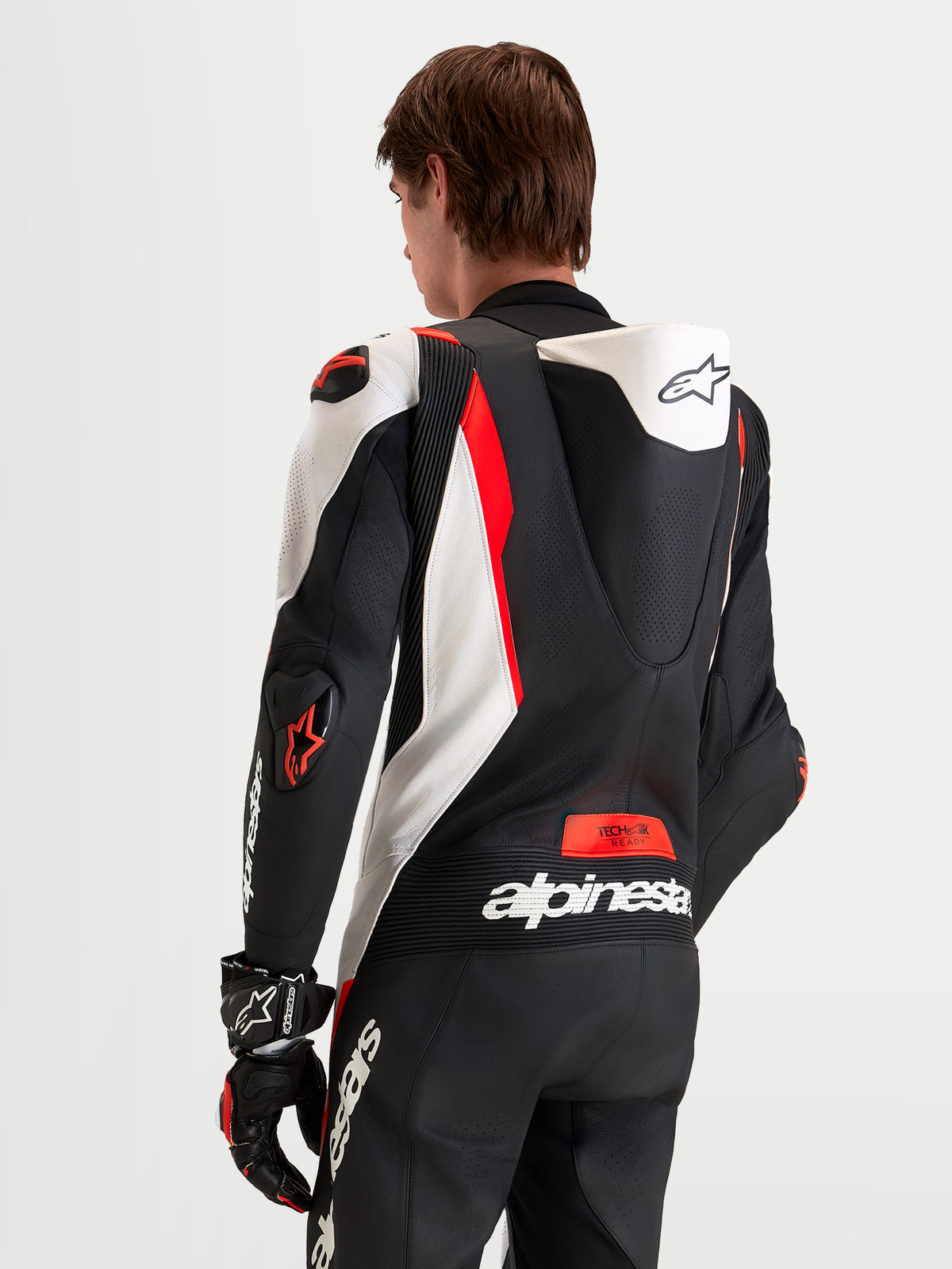 Alpinestars Missile V3 Leather Suit 1-Piece, men's motorcycle racing suit, Black White and Red Fluo, featuring aerodynamic perforated speed hump, DFS shoulder and elbow armor, and accordion stretch panels, rear view on model