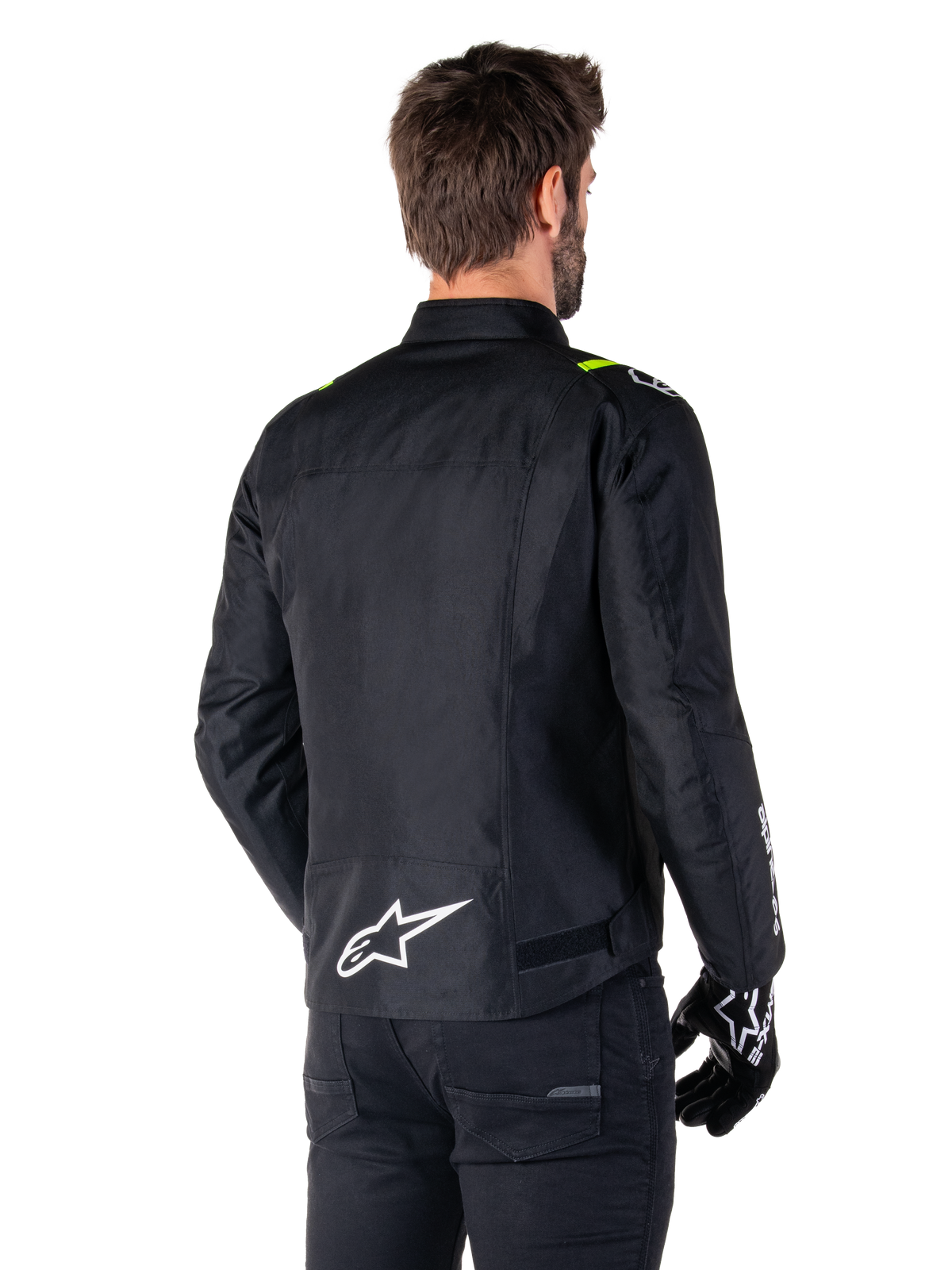 Alpinestars T-SPS V2 Waterproof Jacket, Black White Yellow Fluo, rear view of male model wearing the textile motorcycle jacket, featuring a white logo on the lower back and yellow fluo accents on the shoulders, paired with black pants and gloves.