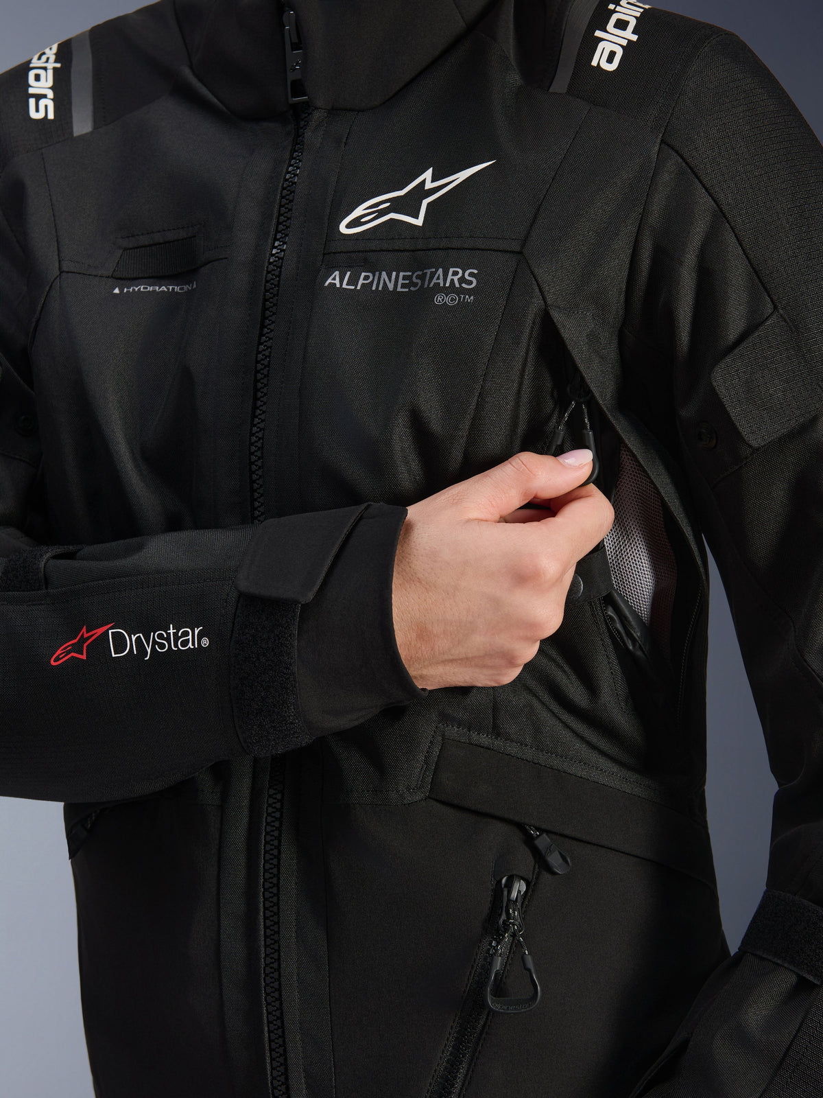 Alpinestars Woman Stella Andes V4 Drystar® Jacket, Black, detail shot showing the chest ventilation intake being opened, featuring mesh lining, Drystar® logo on the forearm, and hydration hose loop, technical motorcycle apparel
