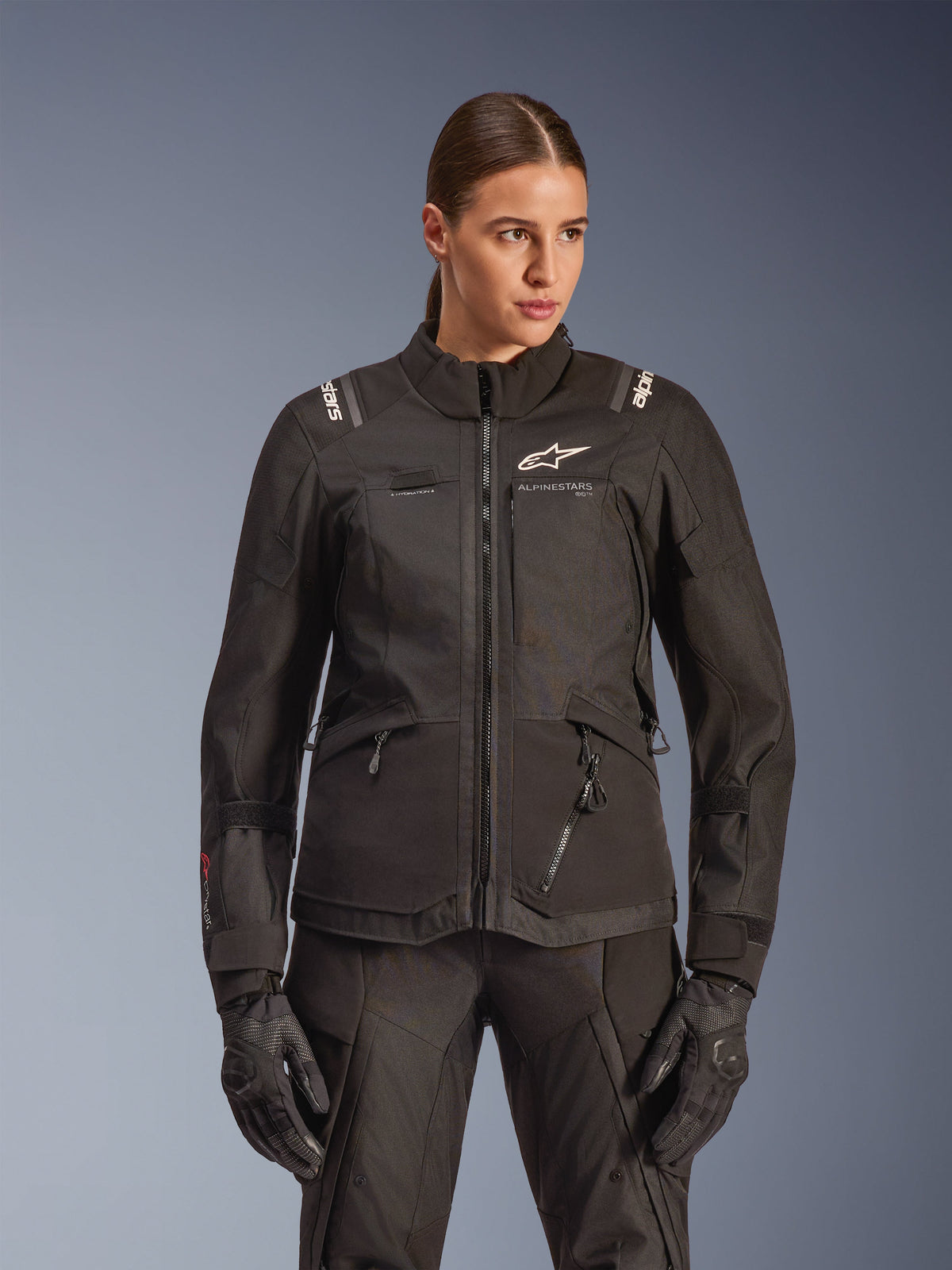 Alpinestars Stella Andes V4 Drystar Jacket, Women's Motorcycle Touring Jacket, Black, worn by a model with matching riding pants and gloves, featuring front zip closure, white logo on chest, and Alpinestars branding on the shoulders, sleek all-weather gear.