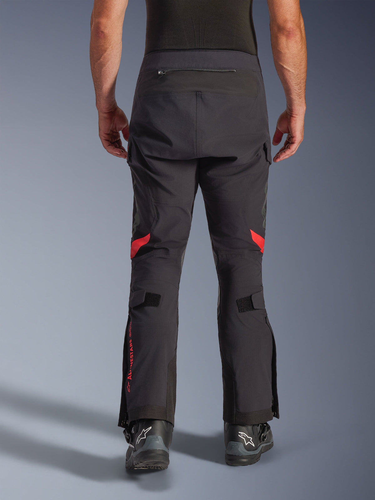 Alpinestars Halo Pro Drystar® XF Laminated Pants, Black Dark Shadow, Rear view of adventure motorcycle pants featuring red accents behind the knees and red branding on the calf, worn with black Alpinestars boots, durable 3L laminated textile for all-terrain performance