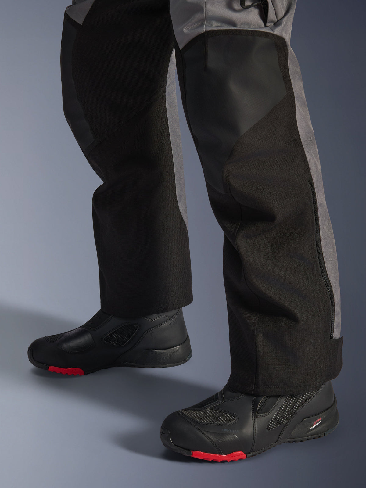 Alpinestars Andes V4 Drystar® Pants, Textile Motorcycle Pants, Black and Dark Gray, worn with black motorcycle boots featuring red soles, adventure touring design with reinforced leg panels and straight-cut fit.
