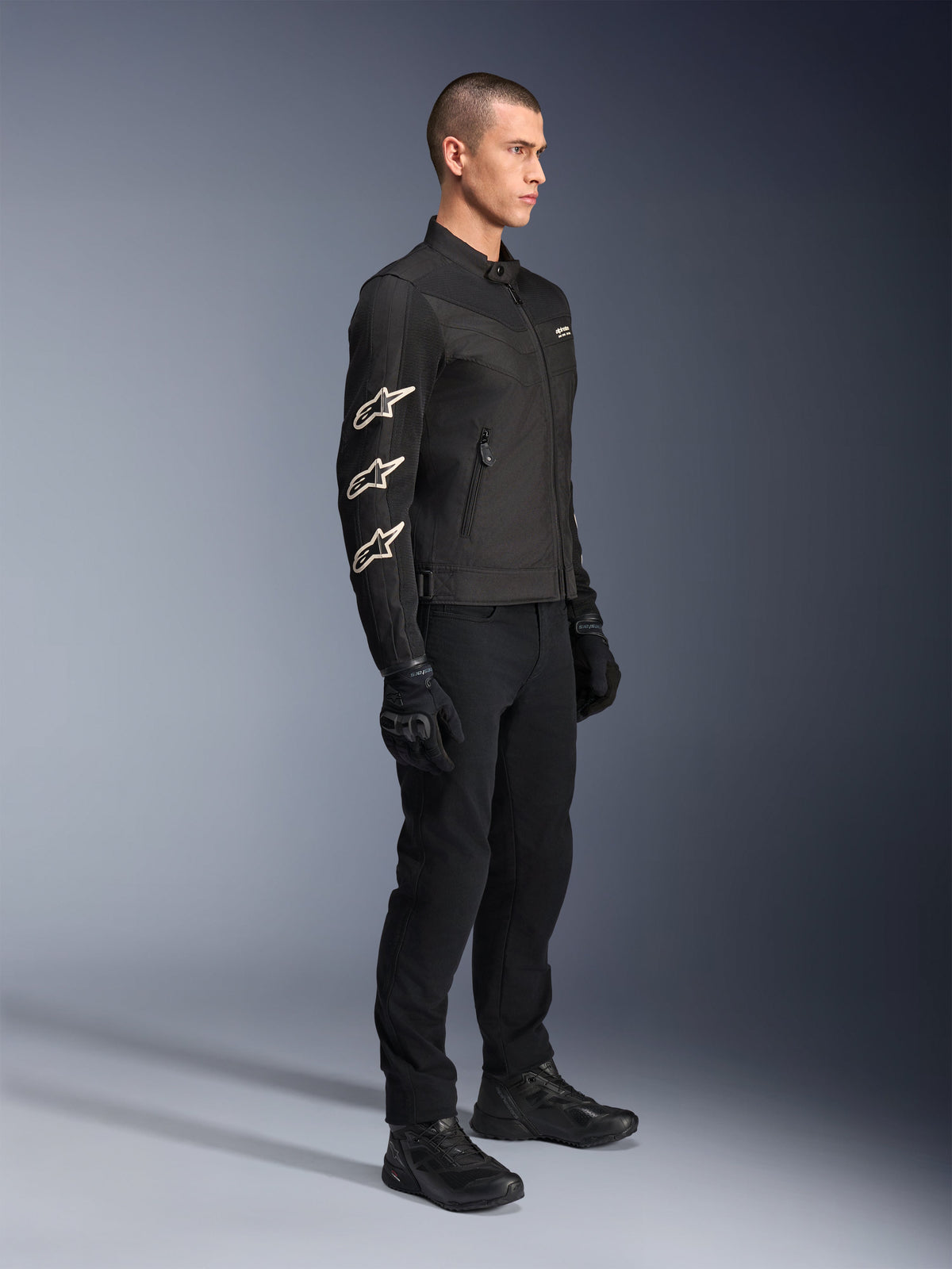 Alpinestars T-Dyno Air Jacket, Black, textile motorcycle jacket, featuring three white Alpinestars logos on the sleeve, worn with matching black pants and gloves, urban riding gear with breathable mesh panels