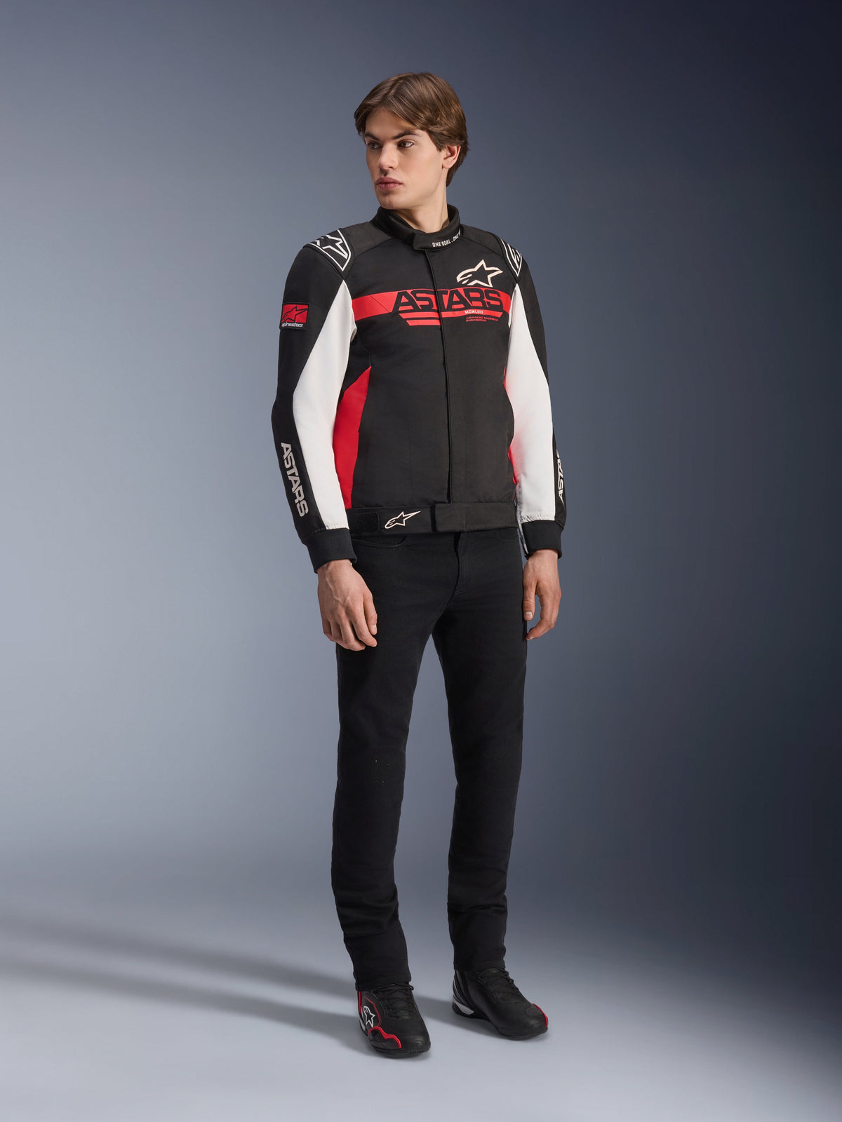 Alpinestars Monza Sport Jacket, Black Bright Red and White, textile motorcycle jacket, racing-inspired design with ASTARS branding across the chest and sleeves, worn by a model with black pants and riding shoes, casual sport riding gear