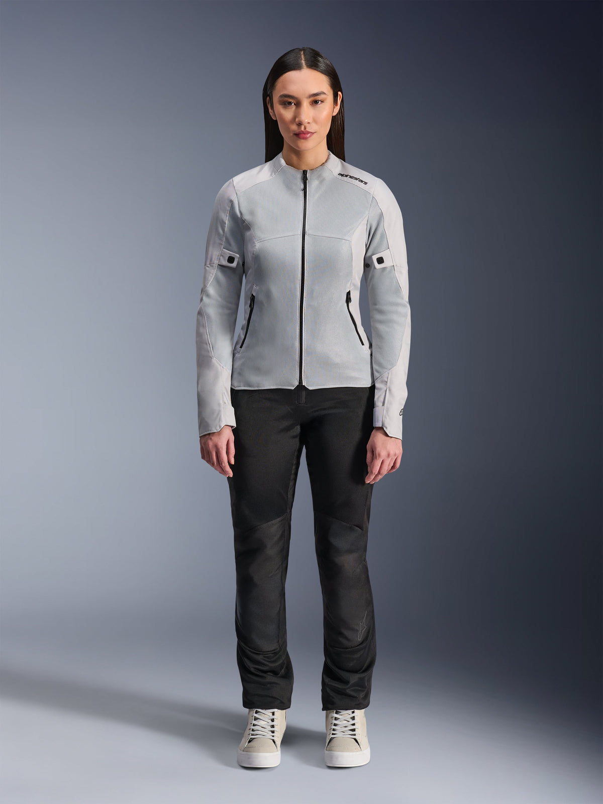 Woman wearing Alpinestars Stella C-1 Air Jacket in Silver, front view, urban motorcycle textile jacket with tech mesh panels, styled with black pants and white sneakers, contemporary riding gear