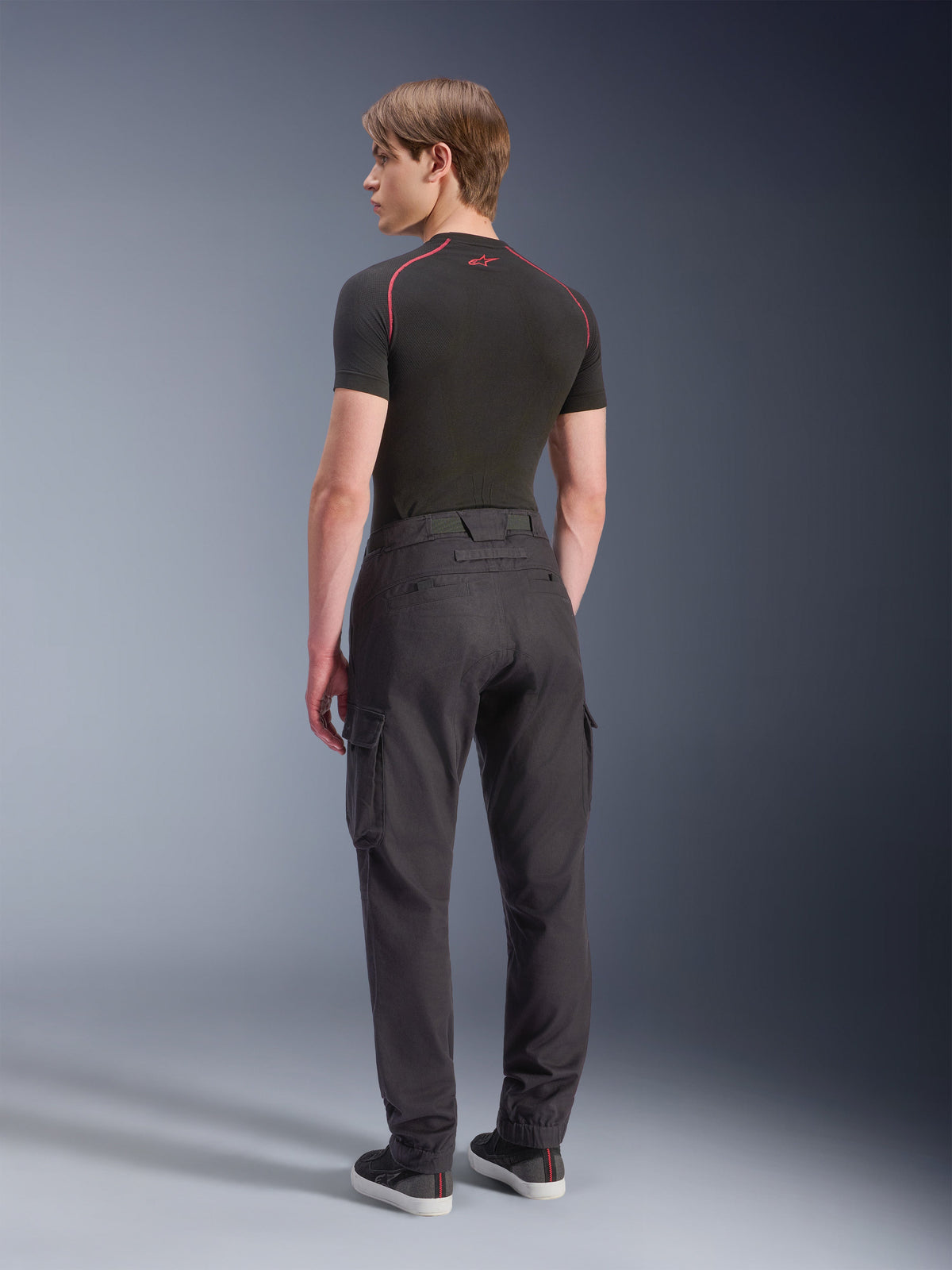 Alpinestars Flex-AST Cargo Pants - Short, Motorcycle Cargo Pants, Black, back view of model wearing regular tapered cargo pants with side pockets and elasticated hems, paired with a black base layer and casual shoes