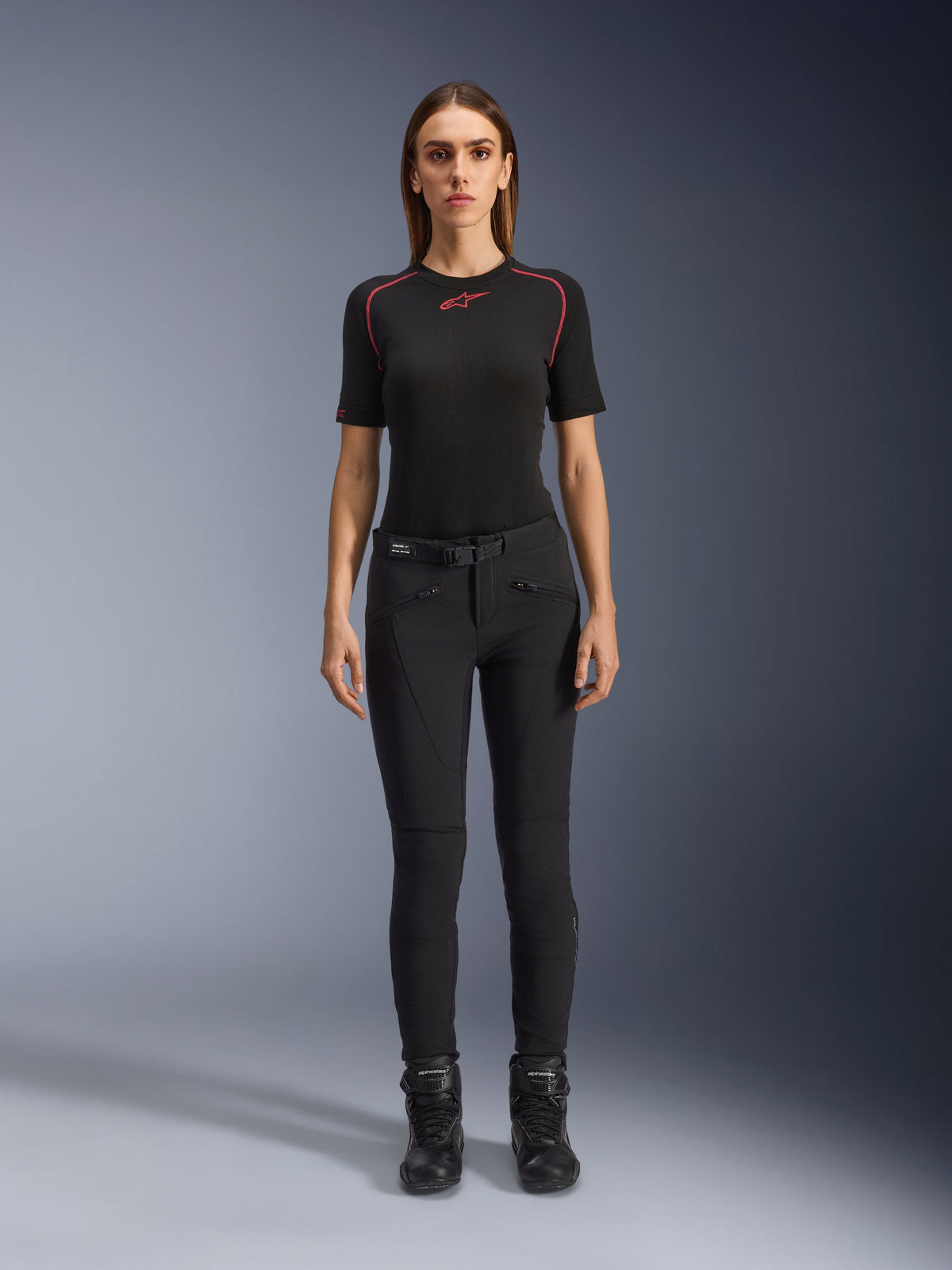 Alpinestars Alamosa Women Pants, slim-fit black motorcycle riding pants, shown on a model facing forward, featuring zippered front pockets and an integrated waist belt, minimalistic streetwear-inspired style for urban riding