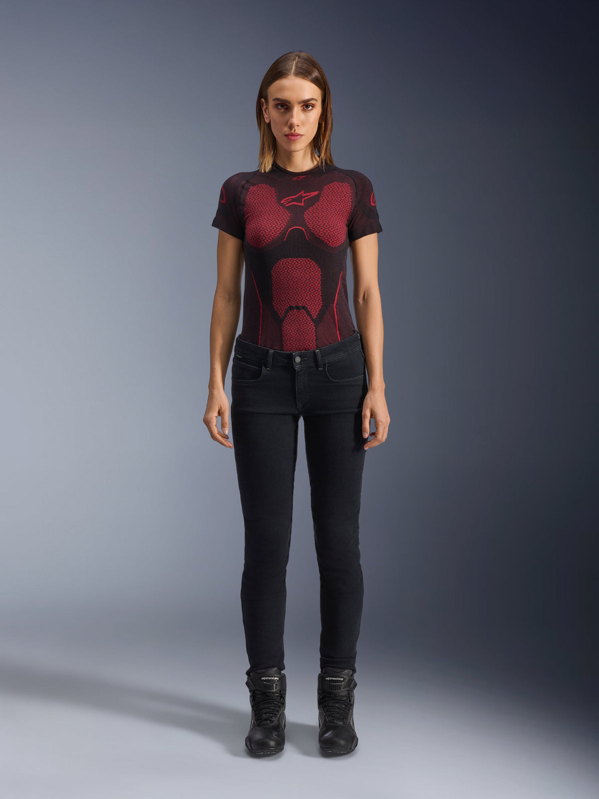 Alpinestars Daisy V3 Women's Riding Denim, Rinse Black, Slim-fit Motorcycle Pants, worn by a model with a red and black patterned technical t-shirt and black motorcycle boots, casual urban riding gear with a feminine silhouette and high-waisted design.