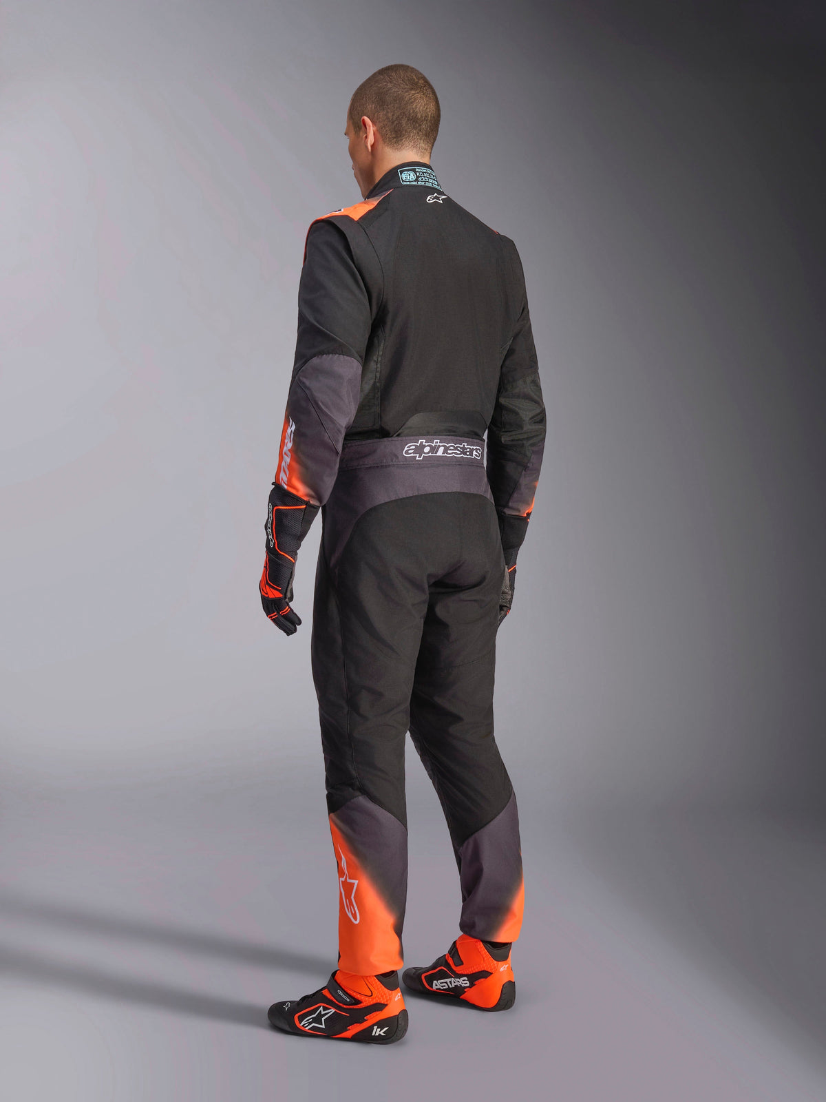 Alpinestars KMX-5 V3 Karting Suit, Men's rear view in black and orange fluo, FIA 8877-2022 Grade 1 certified.