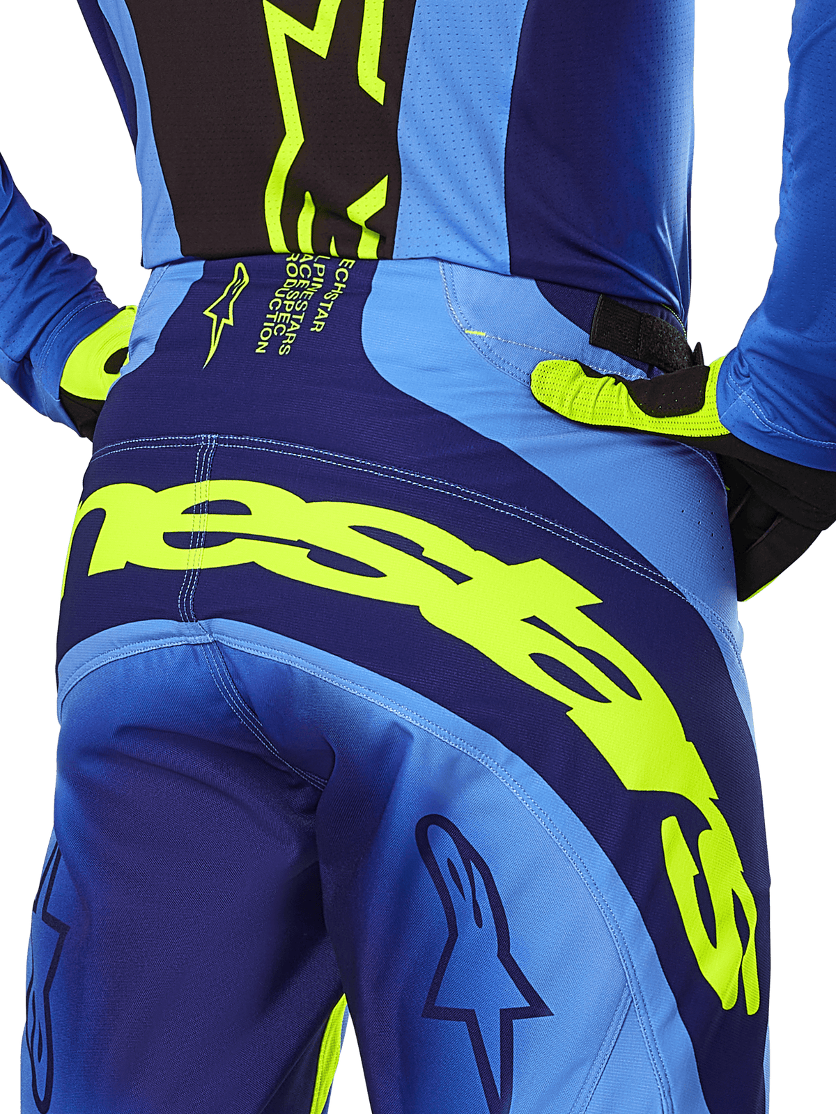 Alpinestars 2025 Techstar Melt Pants, Motocross Pants, Yellow Fluo and Blue, rear view close-up featuring bold yellow Alpinestars branding across the seat, worn with matching blue jersey and yellow-fluo gloves, designed for performance off-road racing.