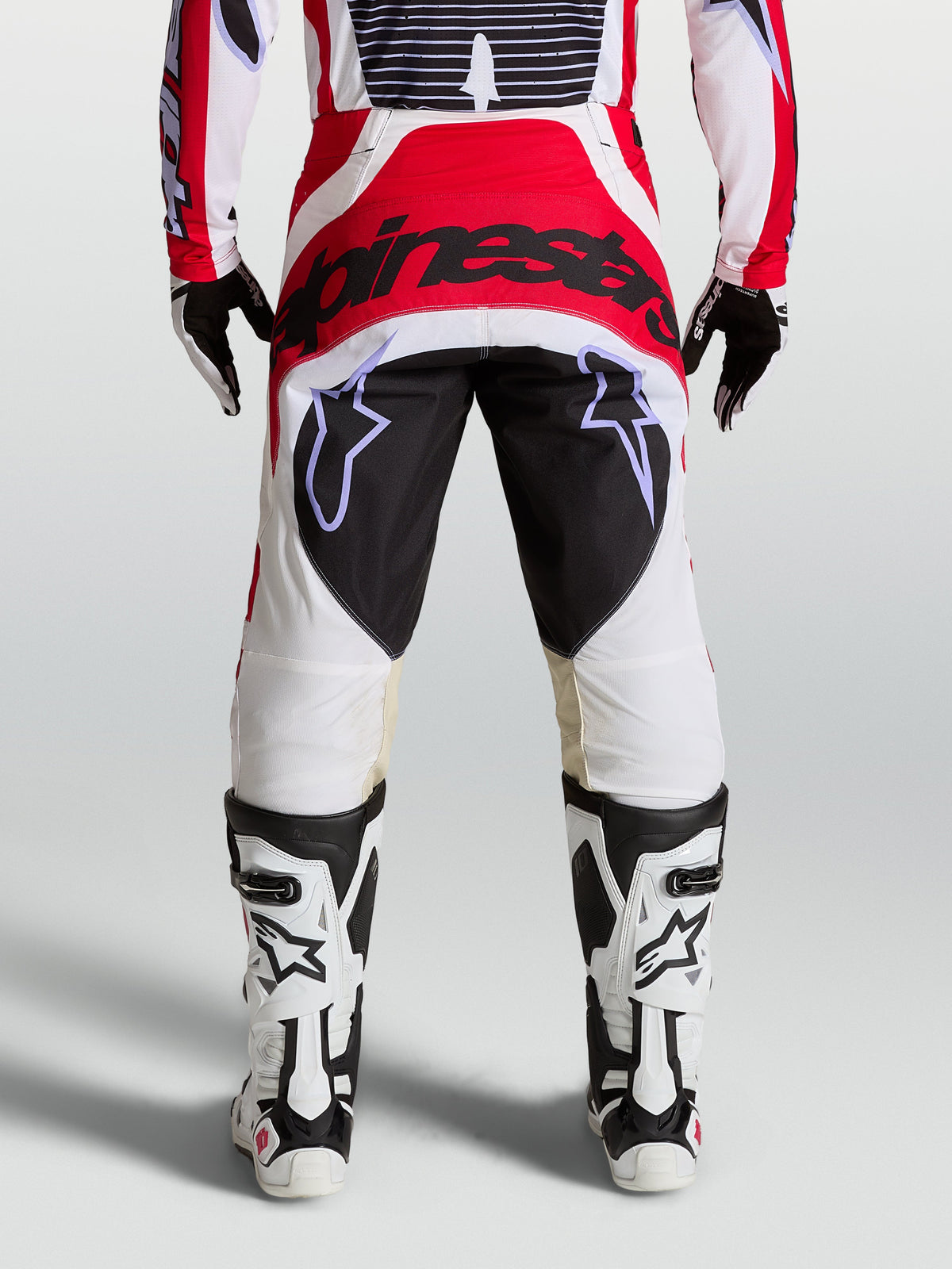 Alpinestars Techstar Maven motocross pants in red, white, and black, featuring a reinforced seat and athletic race fit.