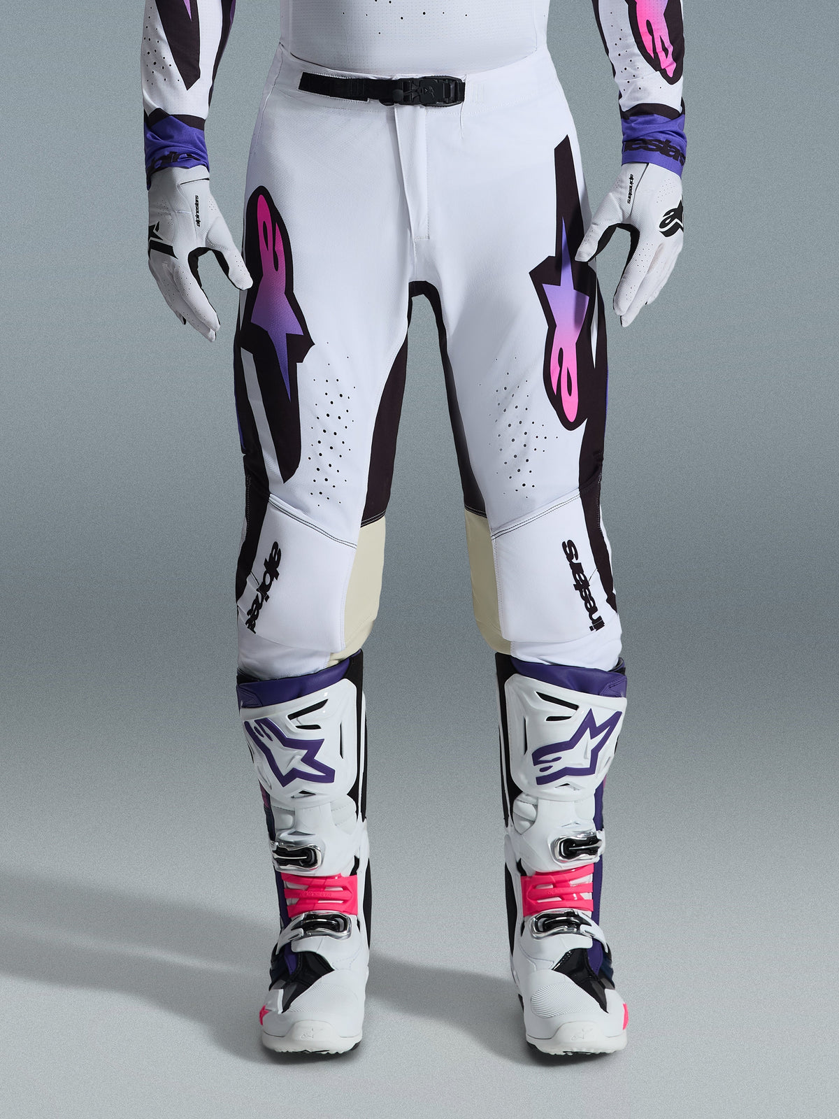 Alpinestars 2026 Supertech AFD Vista Pants, Motocross Pants, White Purple and Black, worn with matching white boots and gloves, featuring pink-to-purple gradient Astars logos on the thighs, professional racing design for off-road performance.