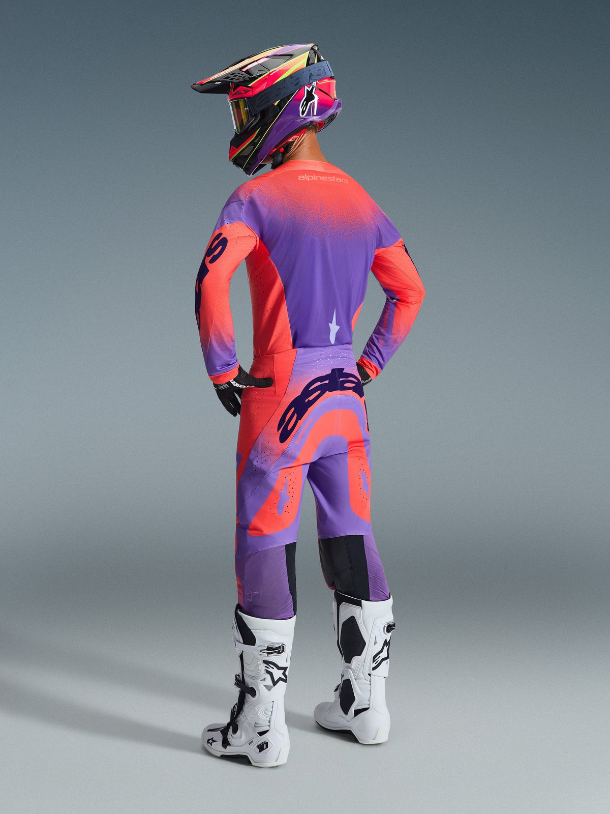 Alpinestars 2026 Supertech Scenz Pants, Motocross Pants, Hot Coral and Purple, rear view showing bold branding on the seat, worn by a rider with a matching jersey and white boots, professional off-road racing gear.