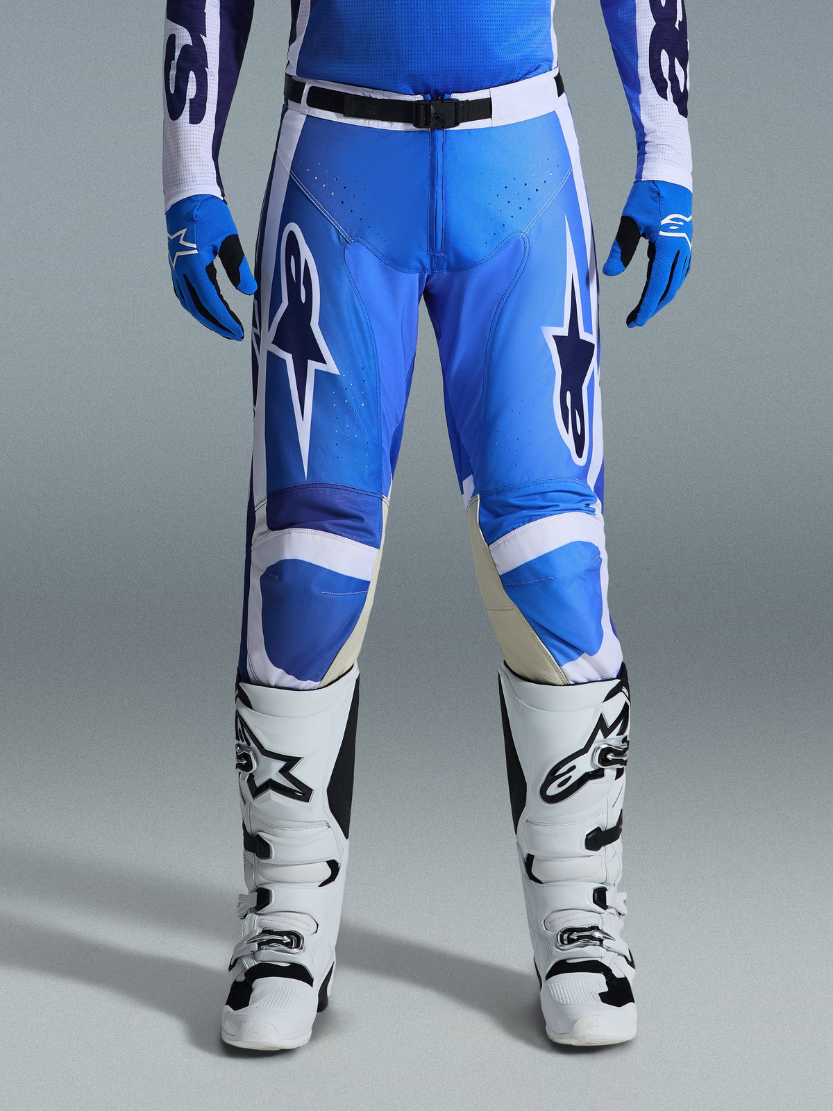 Alpinestars 2026 Racer Air Portl Pants, Motocross Pants, Ucla Blue and White, worn with matching blue gloves and white boots, featuring black waist closure, large white star logos on the thighs, and perforated fabric for enhanced airflow during off-road racing.