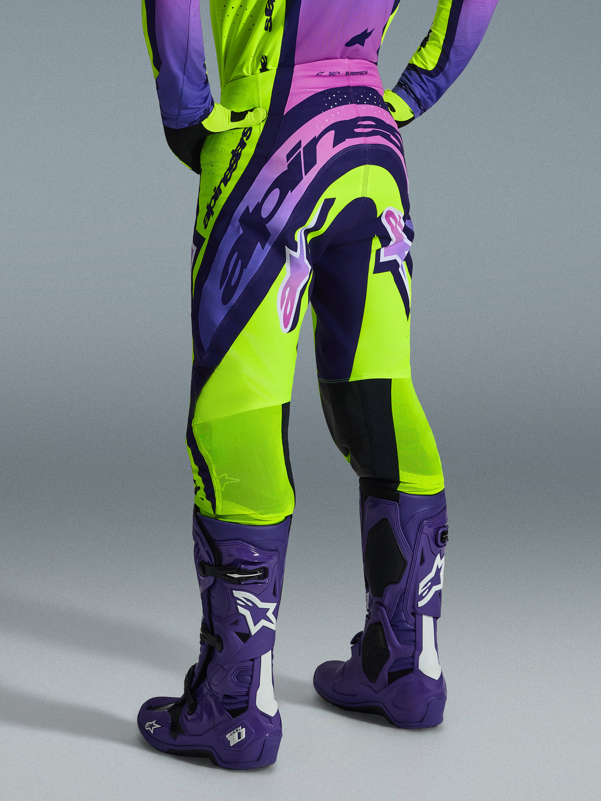 Alpinestars 2026 Supertech Vista Pants, Motocross Pants, Yellow Purple and Black, rear view worn with matching jersey and purple motocross boots, featuring bold branding and breathable mesh zones on the calves