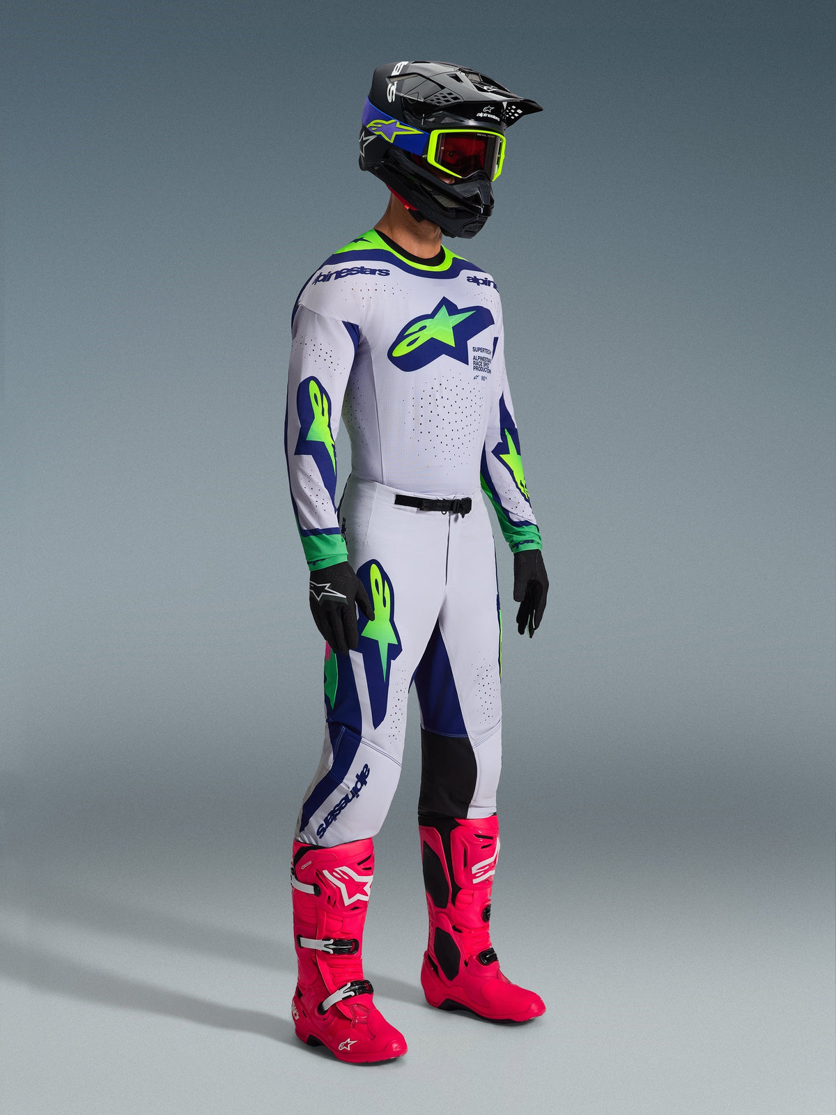 Alpinestars 2026 Supertech Vista Pants and matching jersey, Motocross gear in Light Gray with Yellow Fluo and Blue accents, worn by a rider with a black helmet and vibrant pink boots, featuring bold athletic graphics and professional racing fit